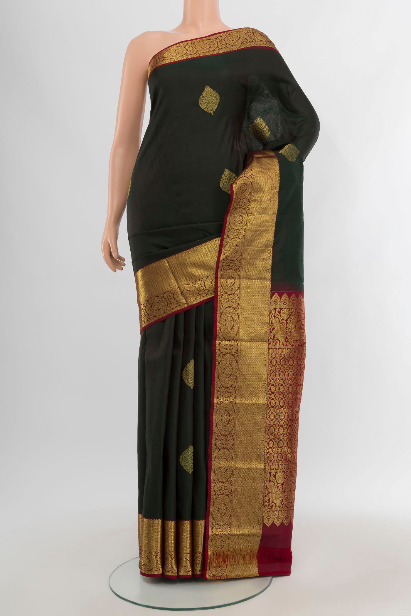 Bottle Green Kanchipuram Silk Saree with Zari Butta on the body and Zari Border.  displayed on a mannequin