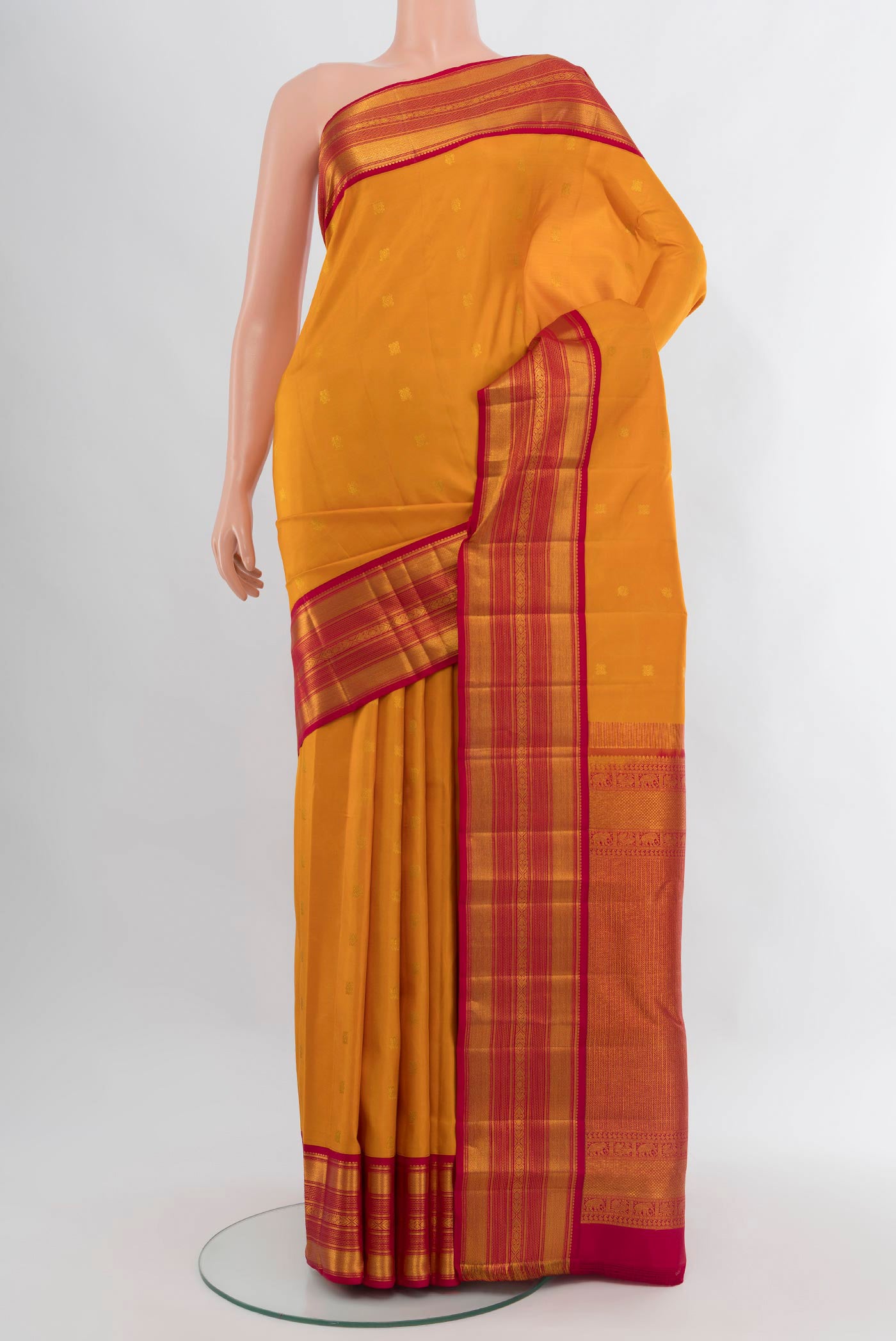 Mustard Kanjivaram Silk Saree with Zari Butta on the body and Zari Border.  displayed on a mannequin