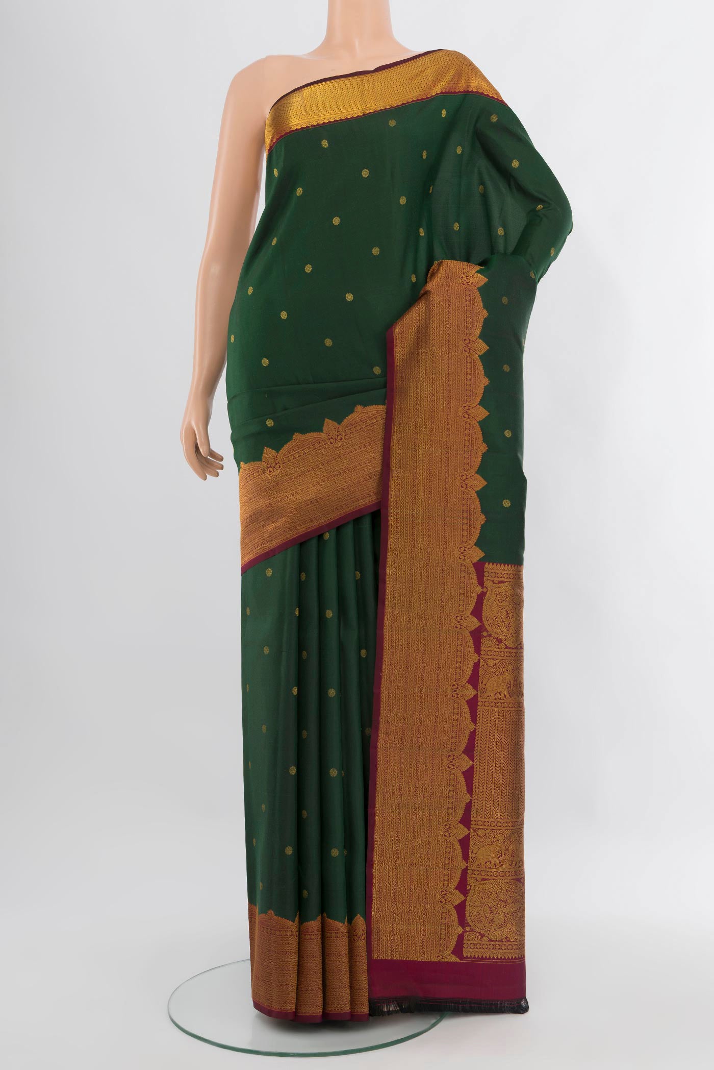 Bottle Green Kanjivaram Silk Saree with Zari Butta on the body and Fancy Border.  displayed on a mannequin