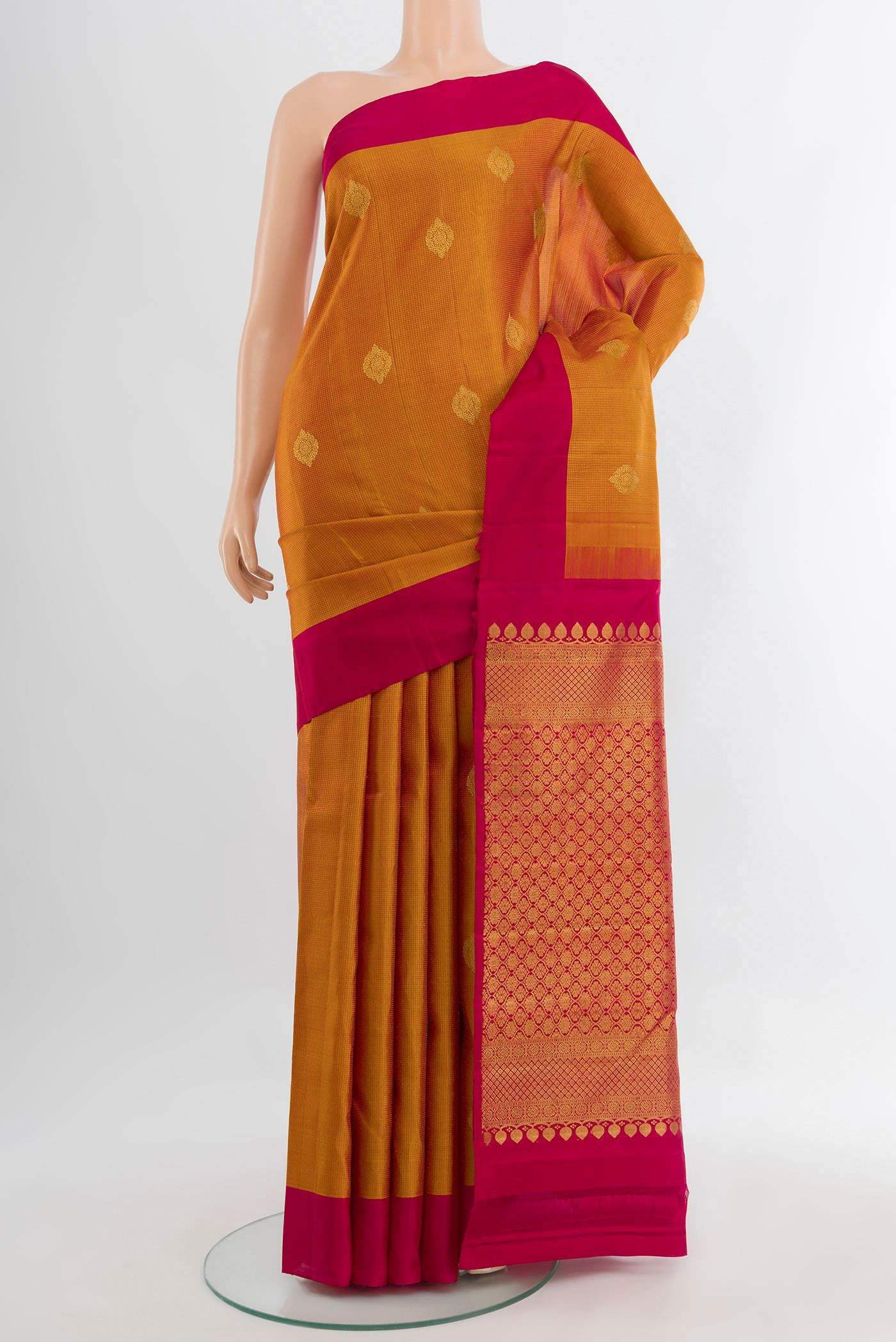 Mustard Kanjivaram Silk Saree with Zari Butta on the body and Silk Border.  displayed on a mannequin