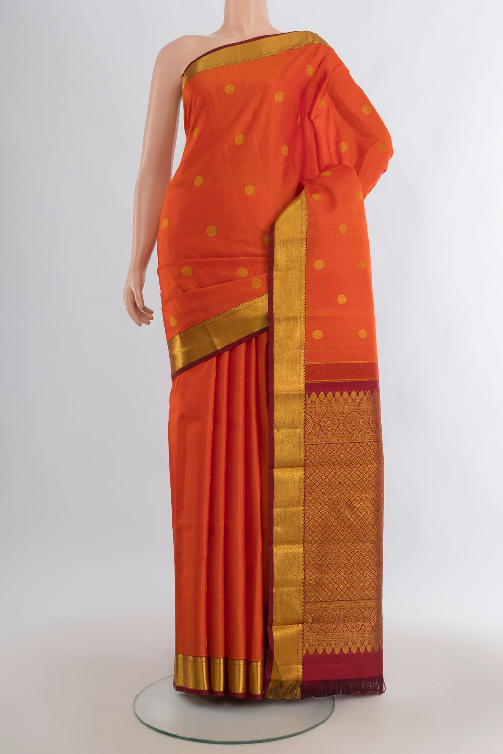 Pure Silk Orange Kanjivaram Saree with Zari Butta on the body and Zari Border.  displayed on a mannequin
