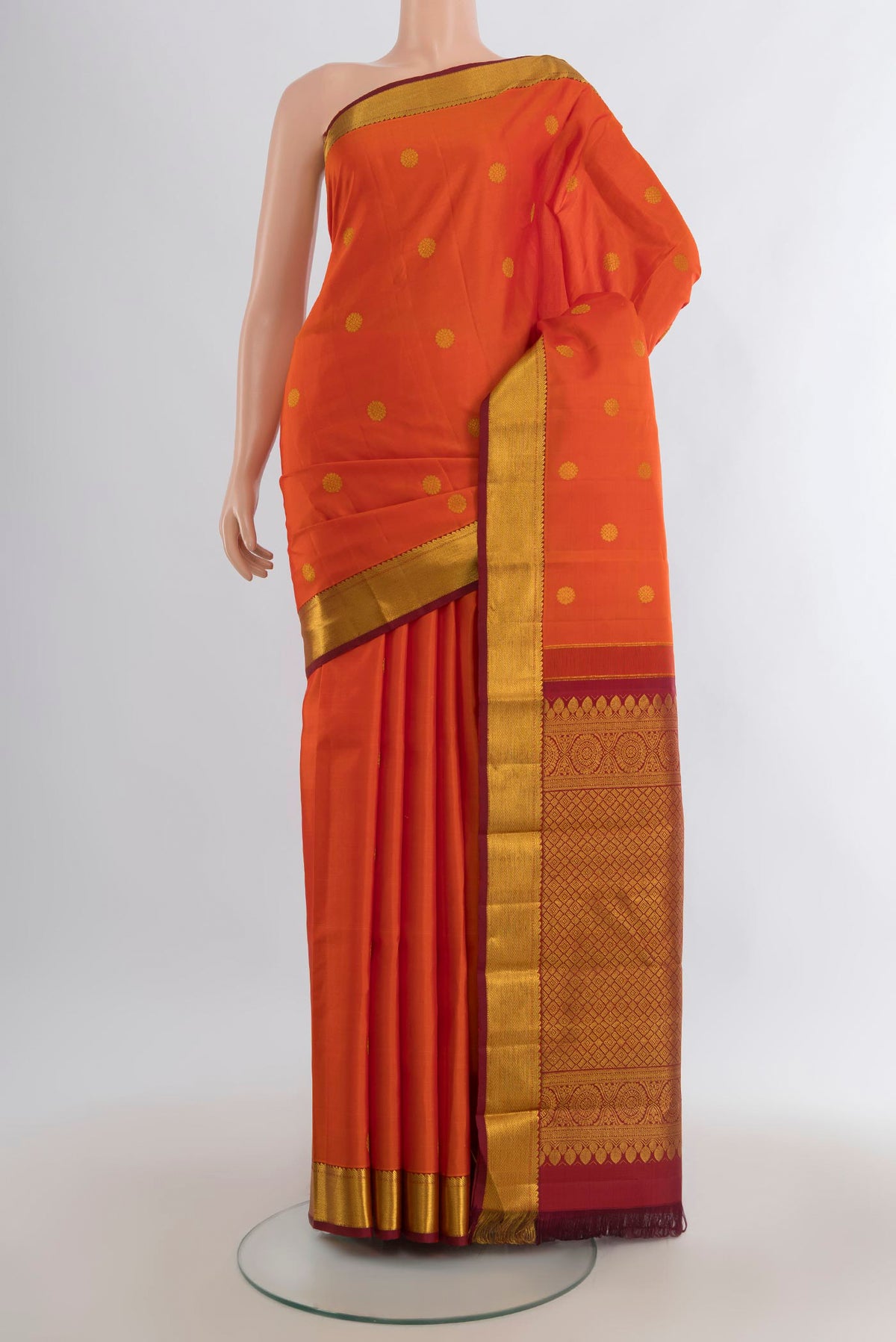 Pure Silk Orange Kanjivaram Saree with Zari Butta on the body and Zari Border.  displayed on a mannequin