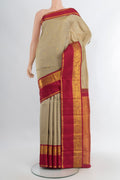 Beige Kanchipuram Silk Saree with Zari Butta on the body and Zari Border.  displayed on a mannequin