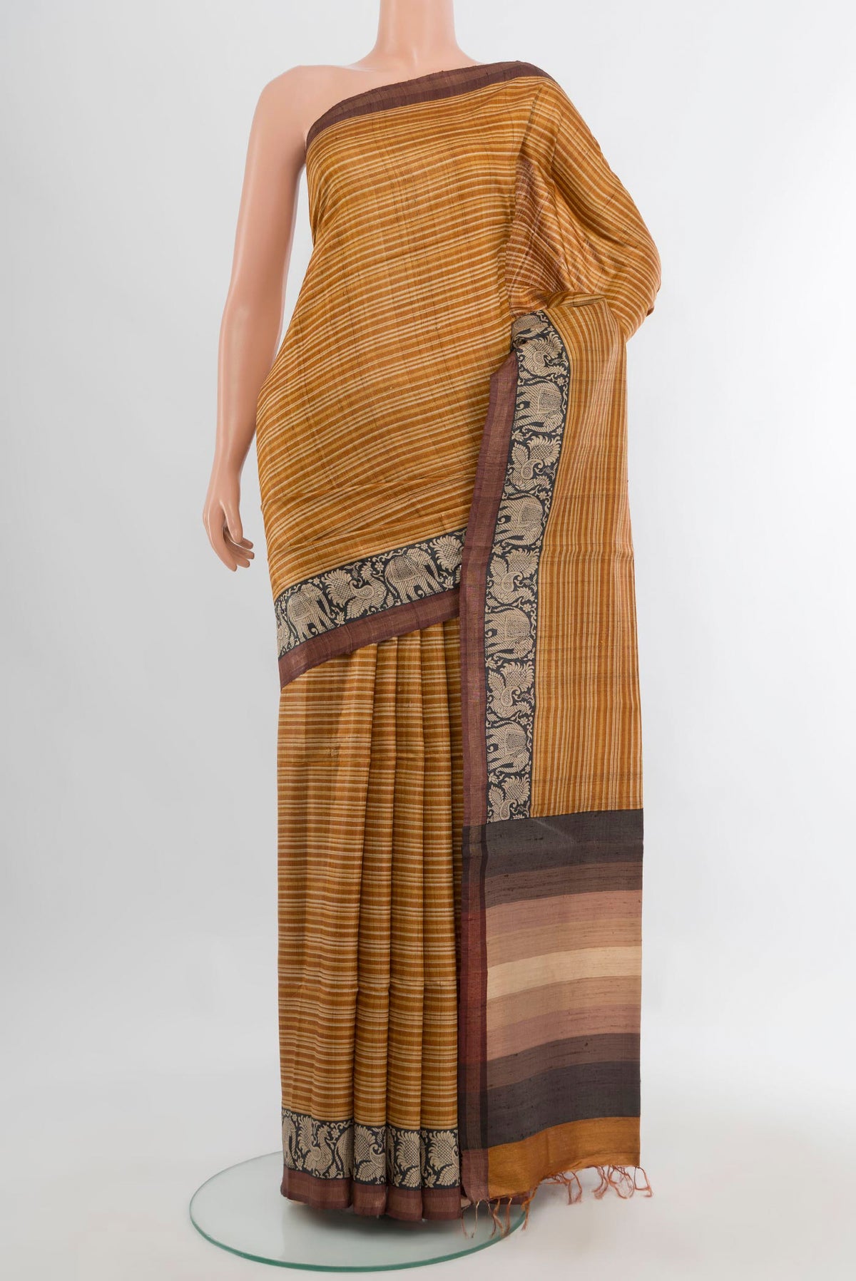 Mustard Tussar Saree with Printed design on the body and Zari Border.  displayed on a mannequin