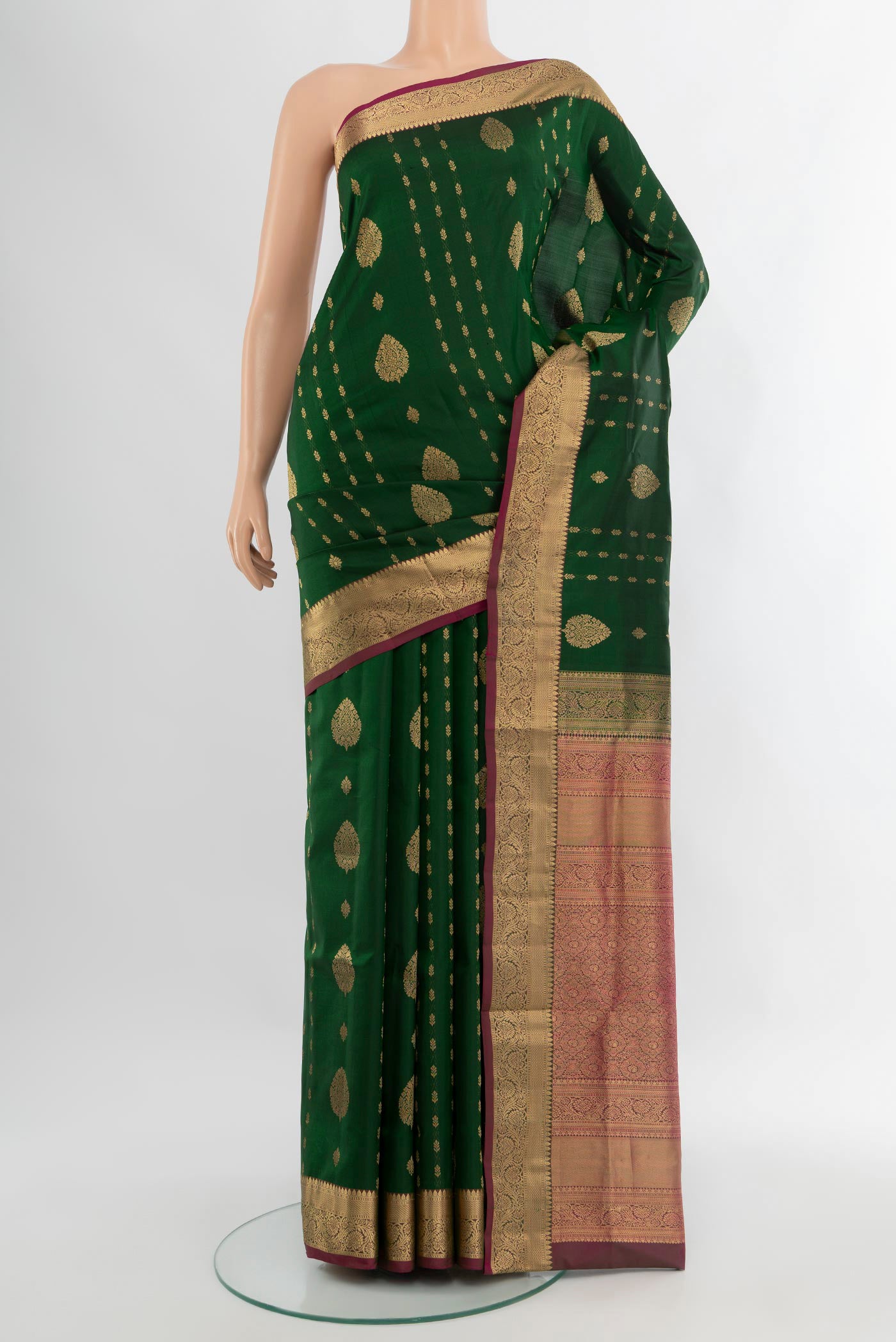 Bottle Green Soft Silk Saree with Zari Butta on the body and Zari Border.  displayed on a mannequin