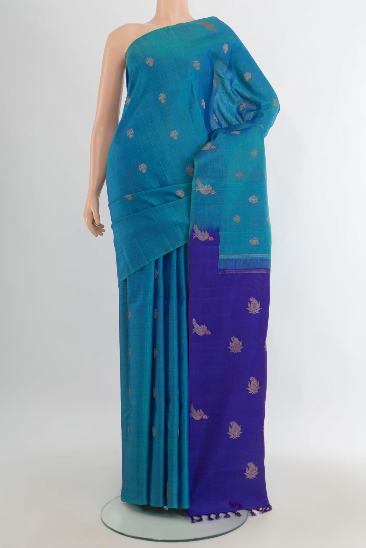 Pure Silk Peacock Blue Kanchipuram Saree with Zari Butta on the body and Without Border.  displayed on a mannequin