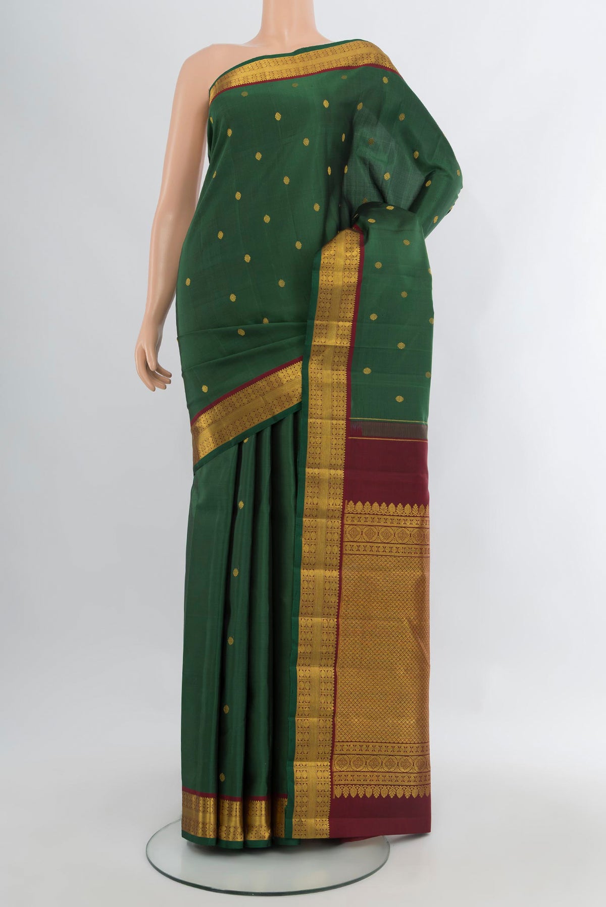 Bottle Green Kanchipuram Silk Saree with Zari Butta on the body and Zari Border.  displayed on a mannequin