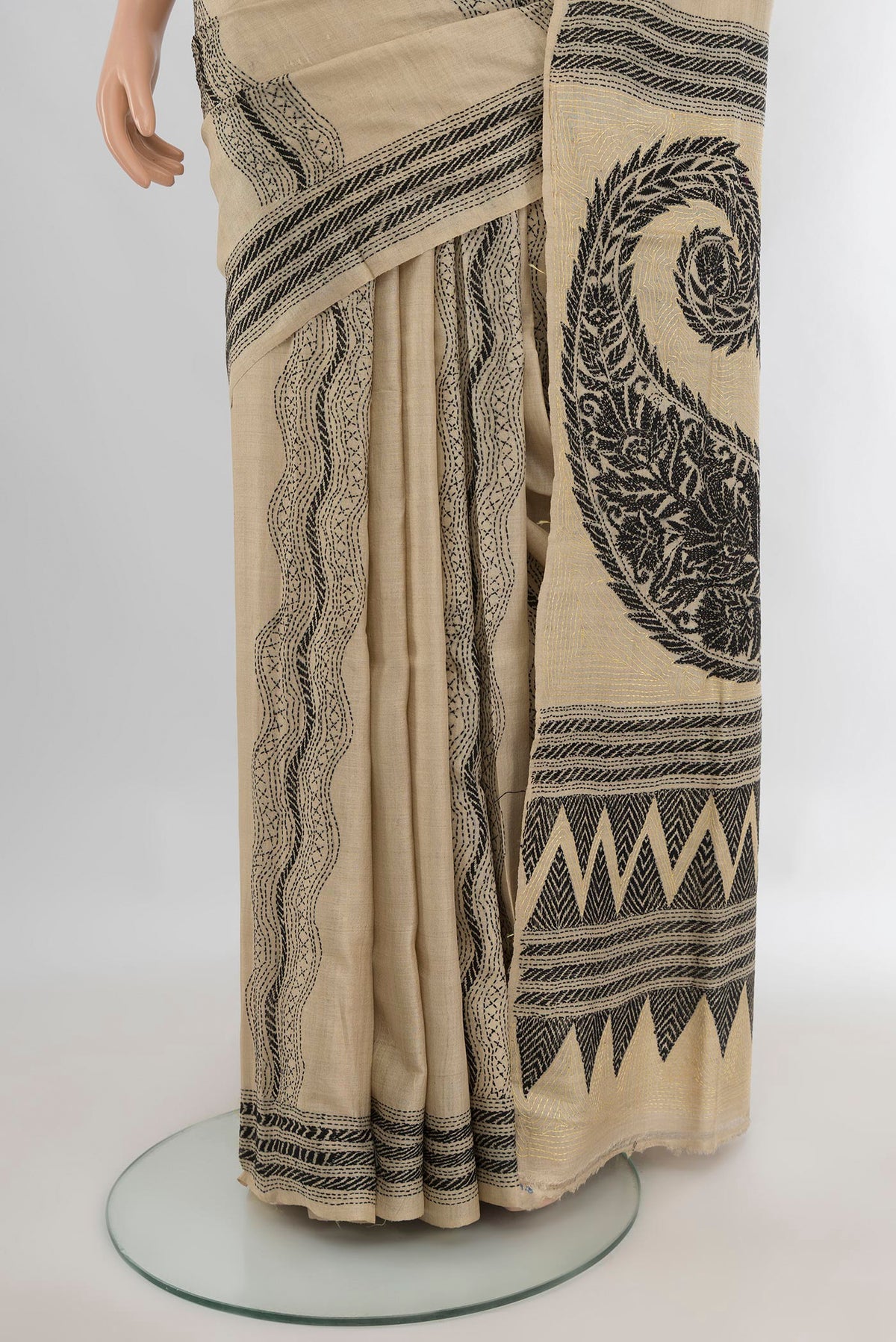 Pleats and pallu of Beige Tussar Saree with Kantha Work on the body and Embroidery Border. 