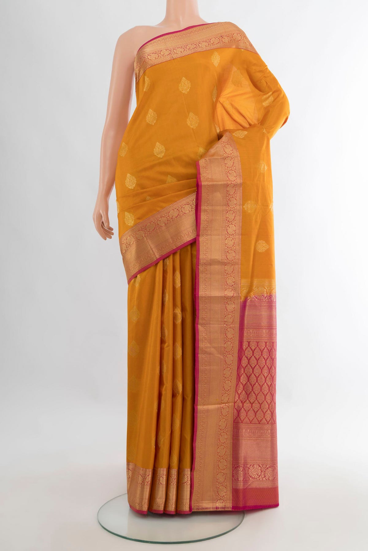 Pure Silk Mustard Soft Saree with Zari Butta on the body and Zari Border.  displayed on a mannequin