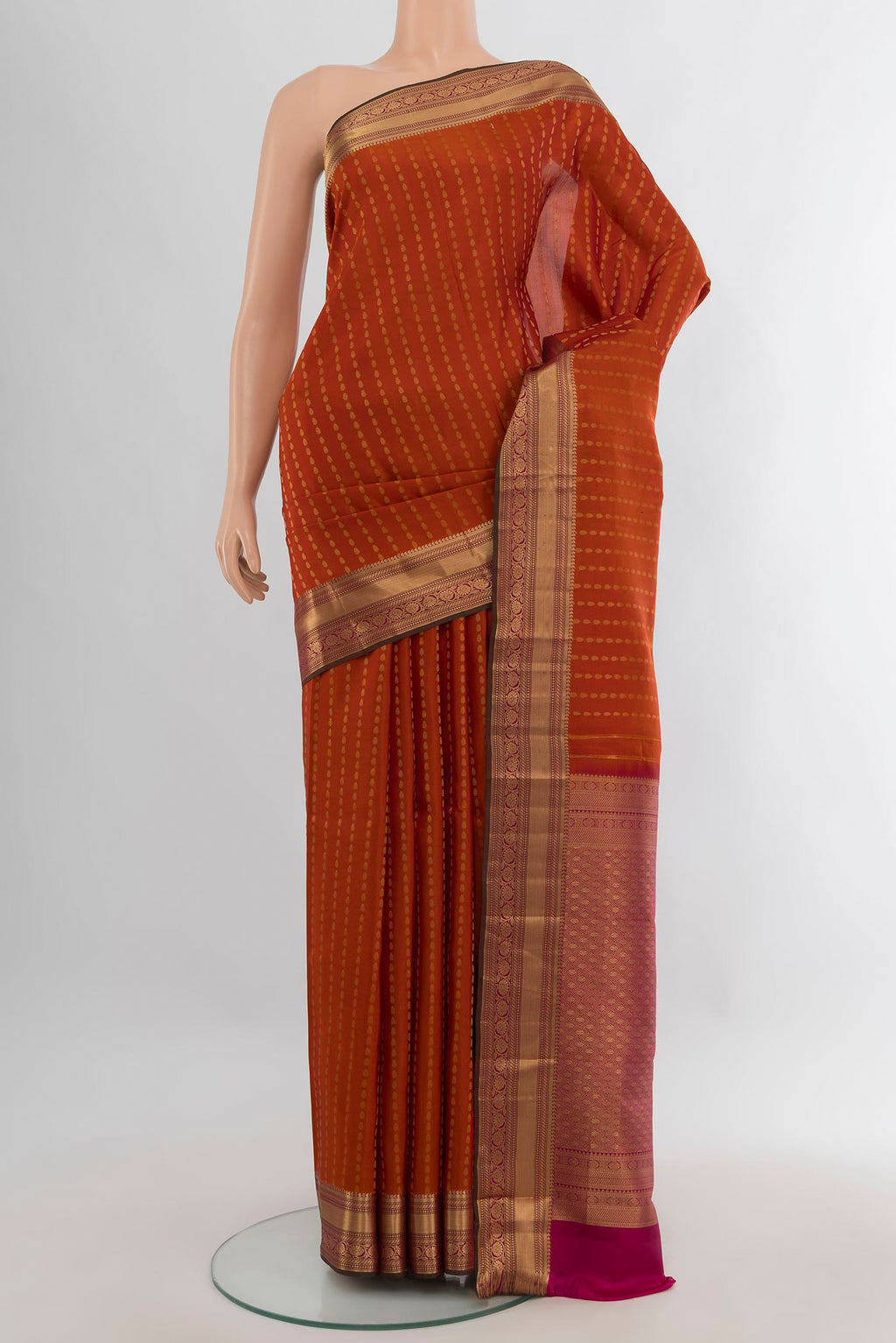 Pure Silk Rust Kanchipuram Saree with Zari Butta on the body and Zari Border.  displayed on a mannequin