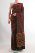 Red Crepe Saree with Printed design on the body and Printed Border.  displayed on a mannequin