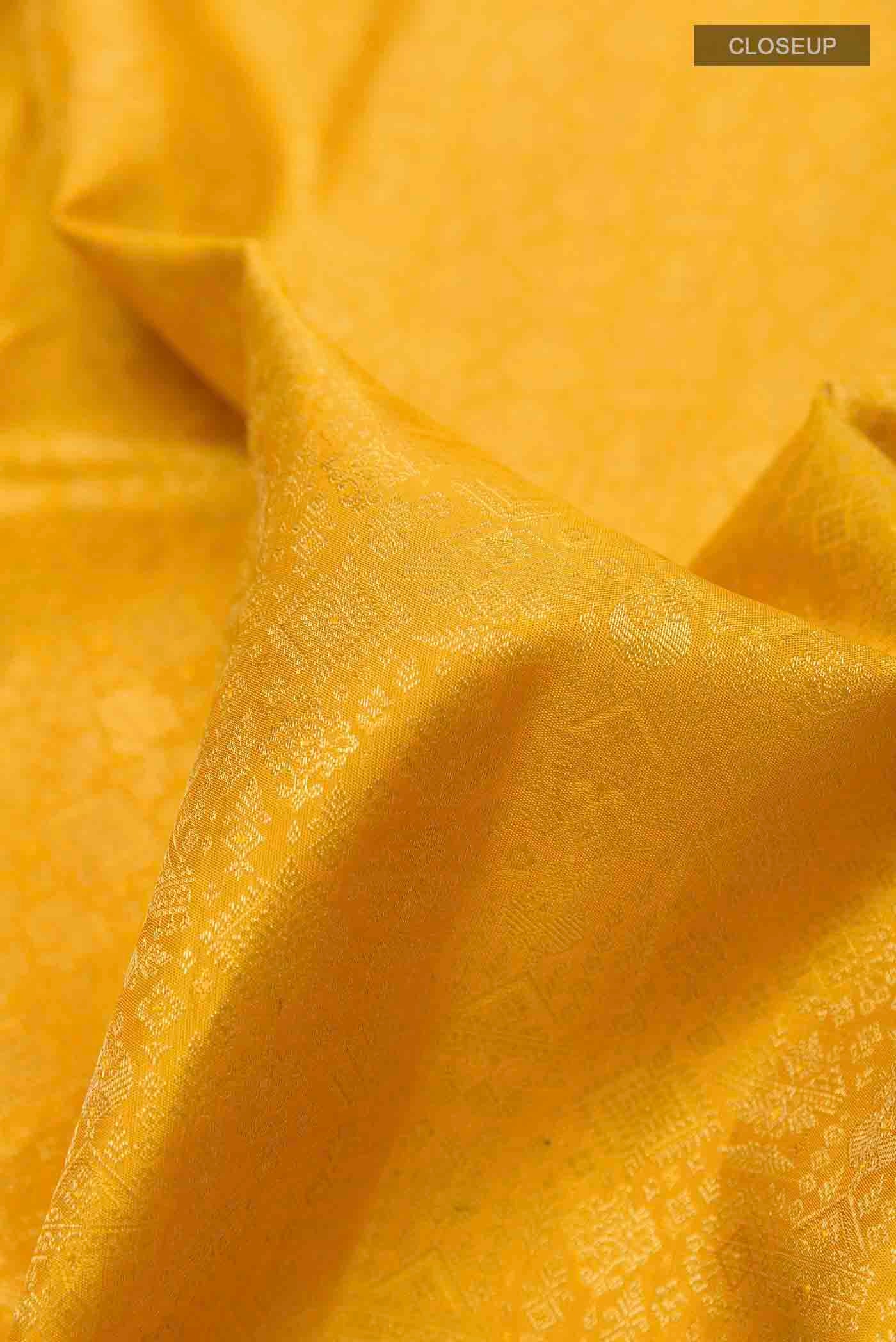Close up of Yellow Dual Tone Kanchipuram Silk Saree with Zari Brocade on the body and Zari Border displaying folds