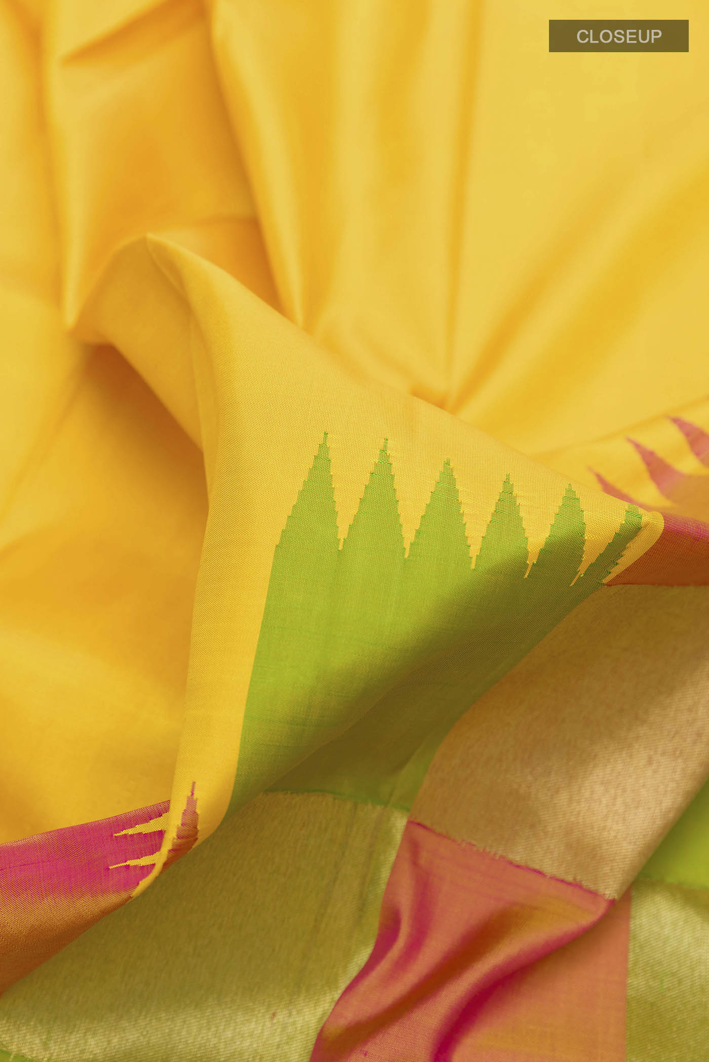 Close up of Yellow Kanchipuram Silk Saree with Plain Body and Rising Temple Border displaying folds