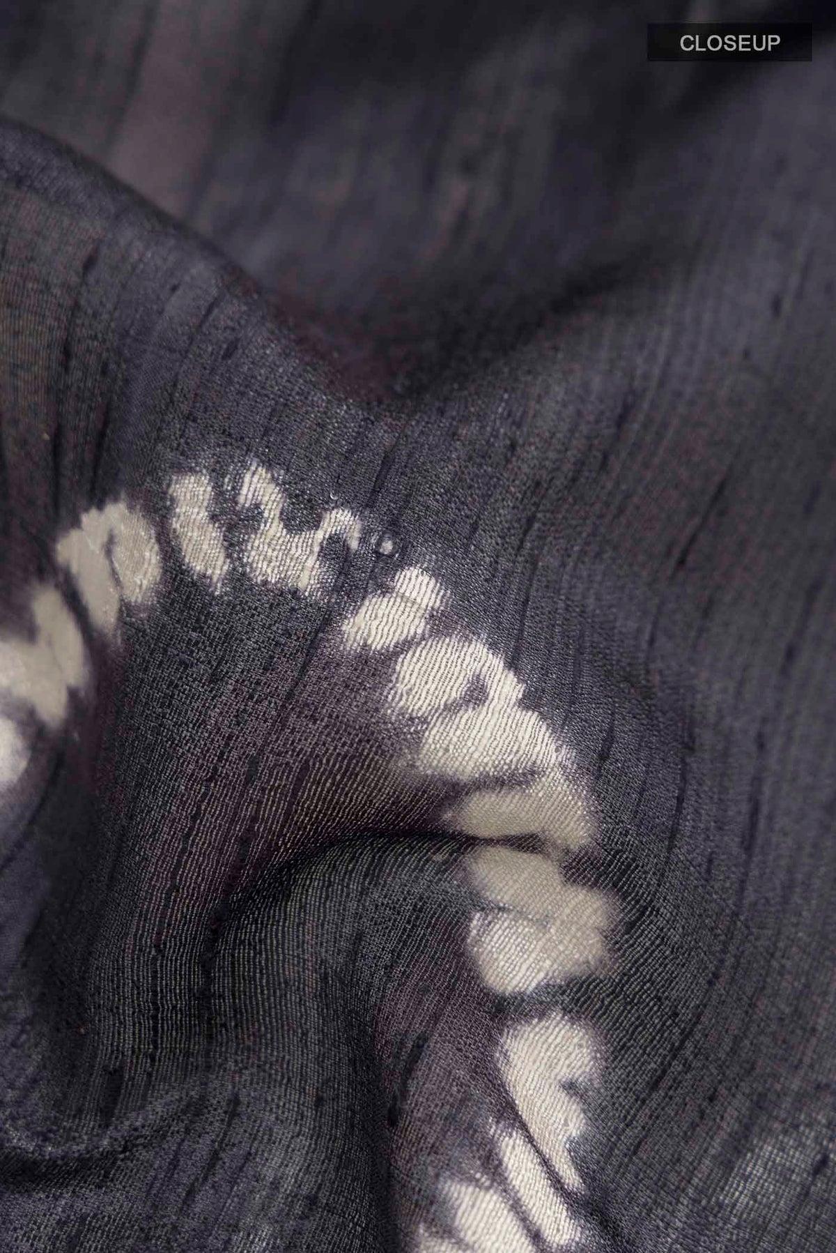 Close up of Grey Raw Silk Saree with Printed design on the body and Zari Border displaying folds