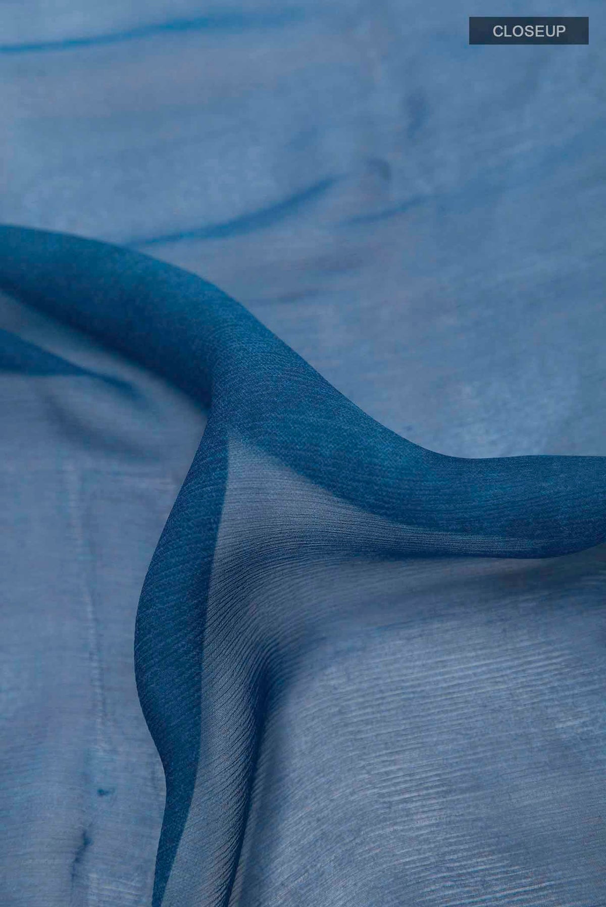 Close up of Peacock Blue Mysore Chiffon Saree with Printed design on the body and Zari Border displaying folds
