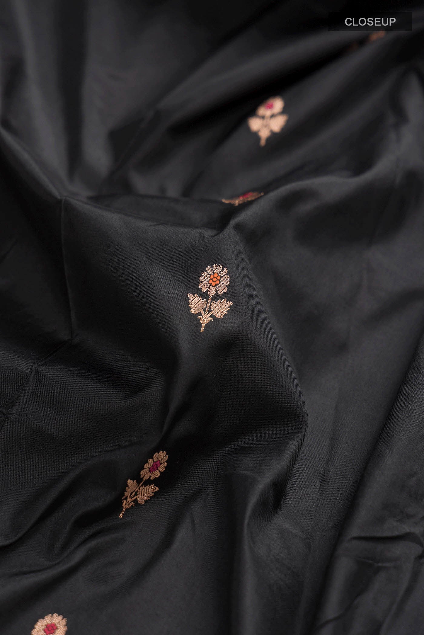 Close up of Black Banarasi Katan Silk Saree with Zari Butta on the body and Zari Border displaying folds