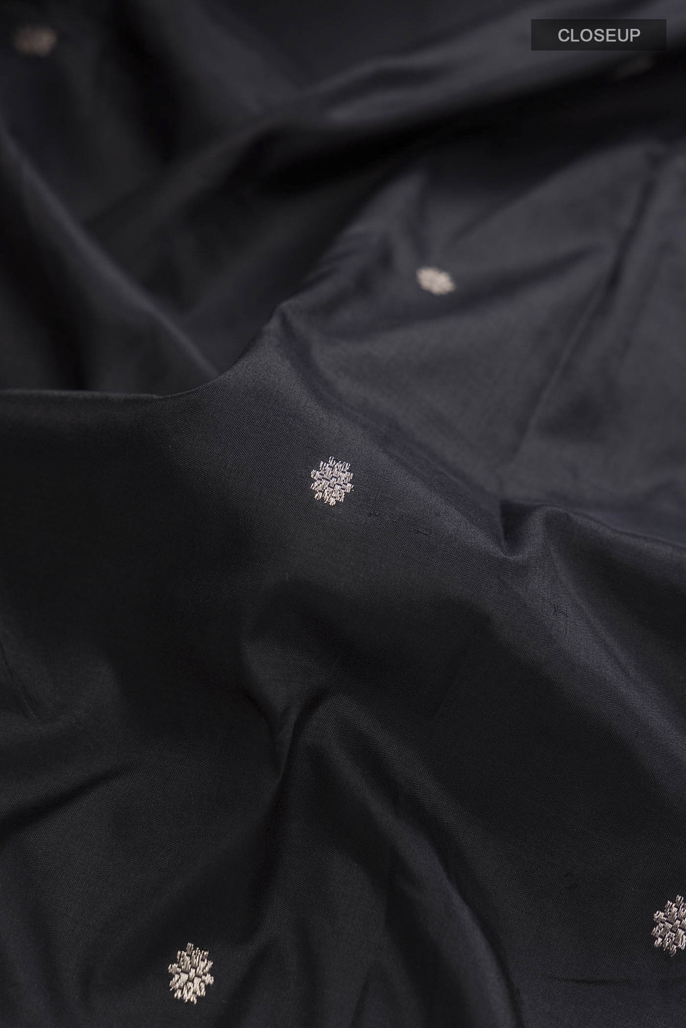 Close up of Black Banarasi Katan Silk Saree with Zari Butta on the body and Zari Border displaying folds