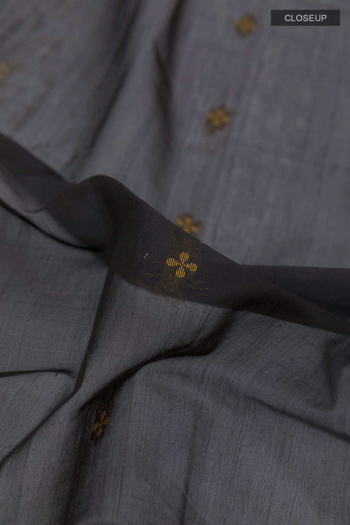 Close up of Black Blended Kora Cotton Saree with Zari And Thread Butta on the body and Zari Border displaying folds