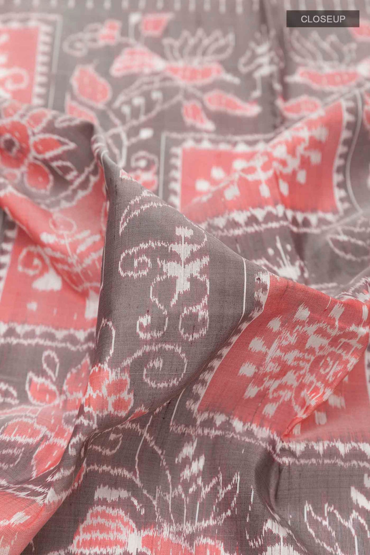 Close up of Grey Orissa Silk Saree with Ikat design on the body and Zari Border displaying folds