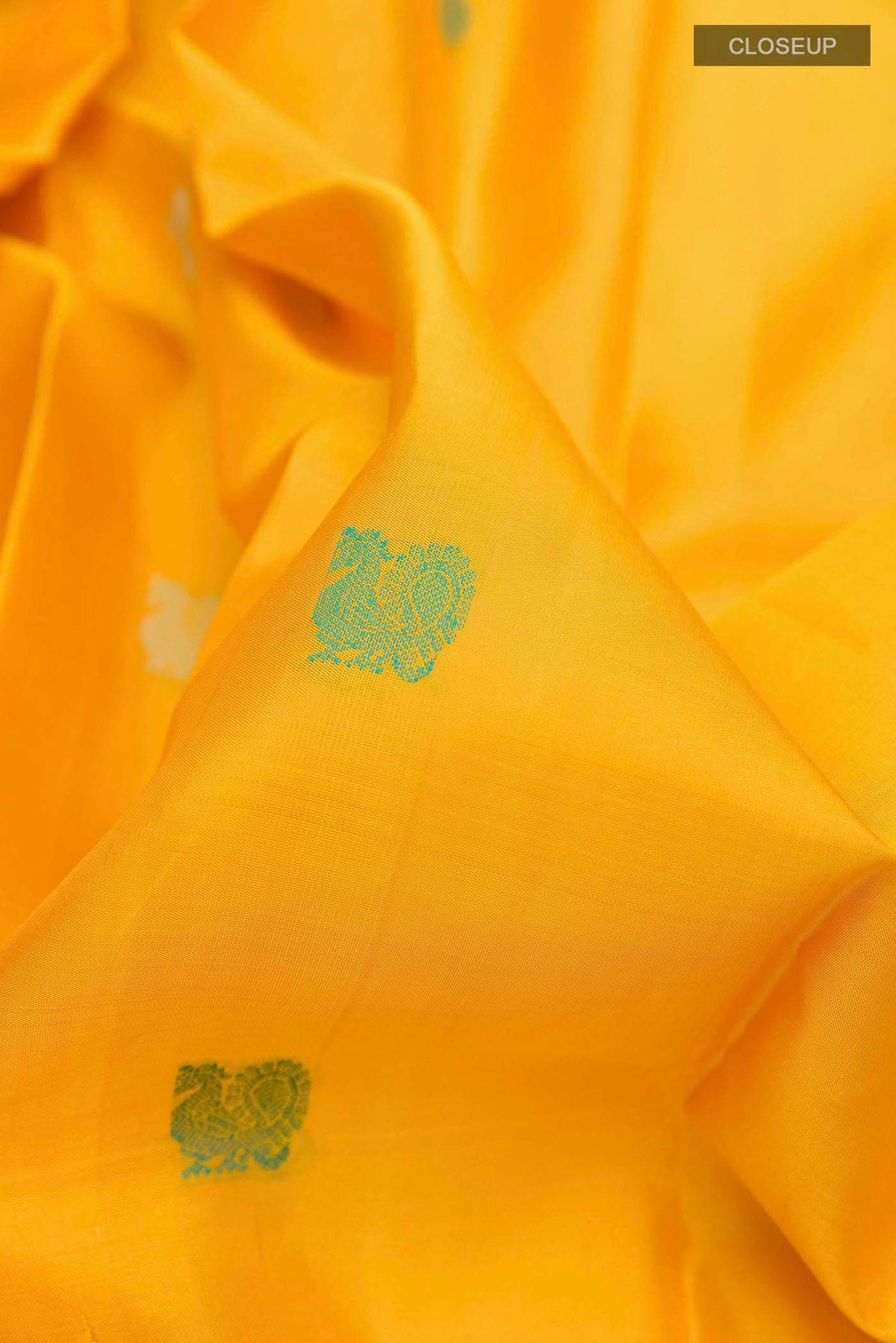 Close up of Yellow Kanchipuram Silk Saree with Thread Butta on the body and Zari And Thread Border displaying folds