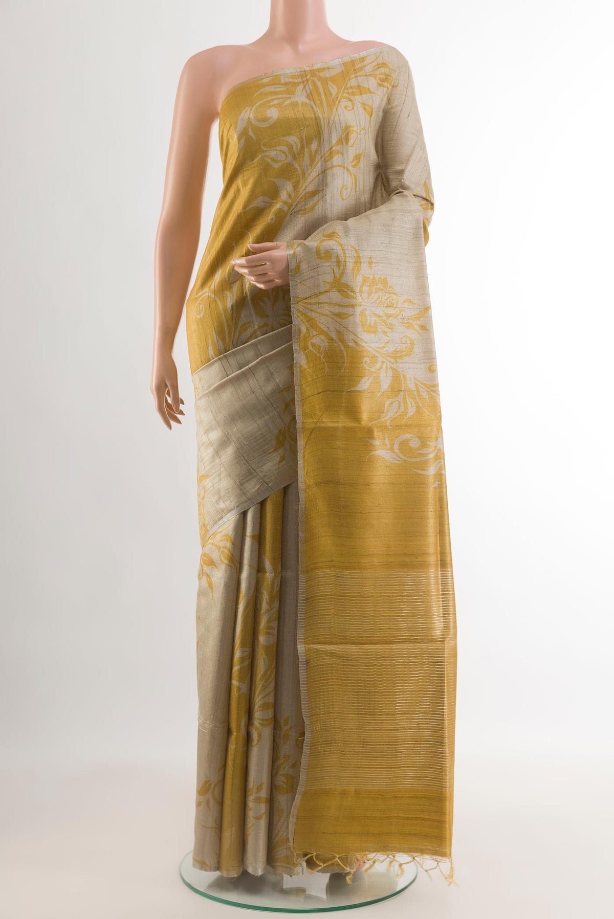 Beige Tussar Silk Saree with Printed design on the body and Thin Zari Line.  displayed on a mannequin