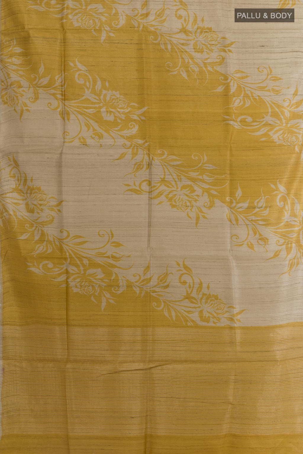 Flat view of Beige Tussar Silk Saree with Printed design on the body and Thin Zari Line. 