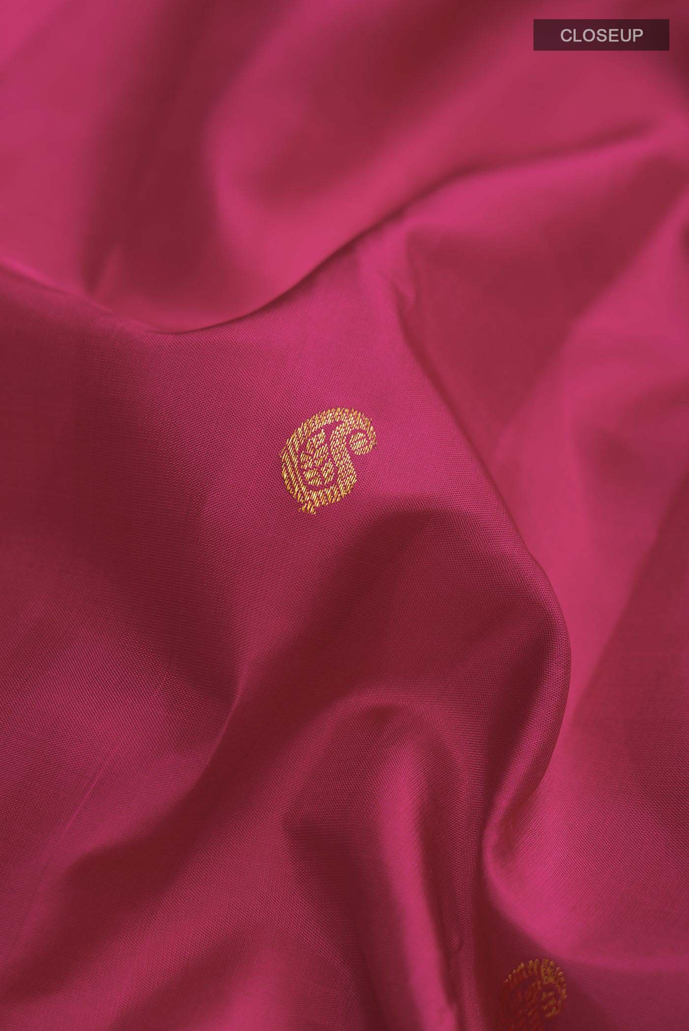 Close up of Pink Kanchipuram Silk Saree with Zari Butta on the body and Zari Border displaying folds