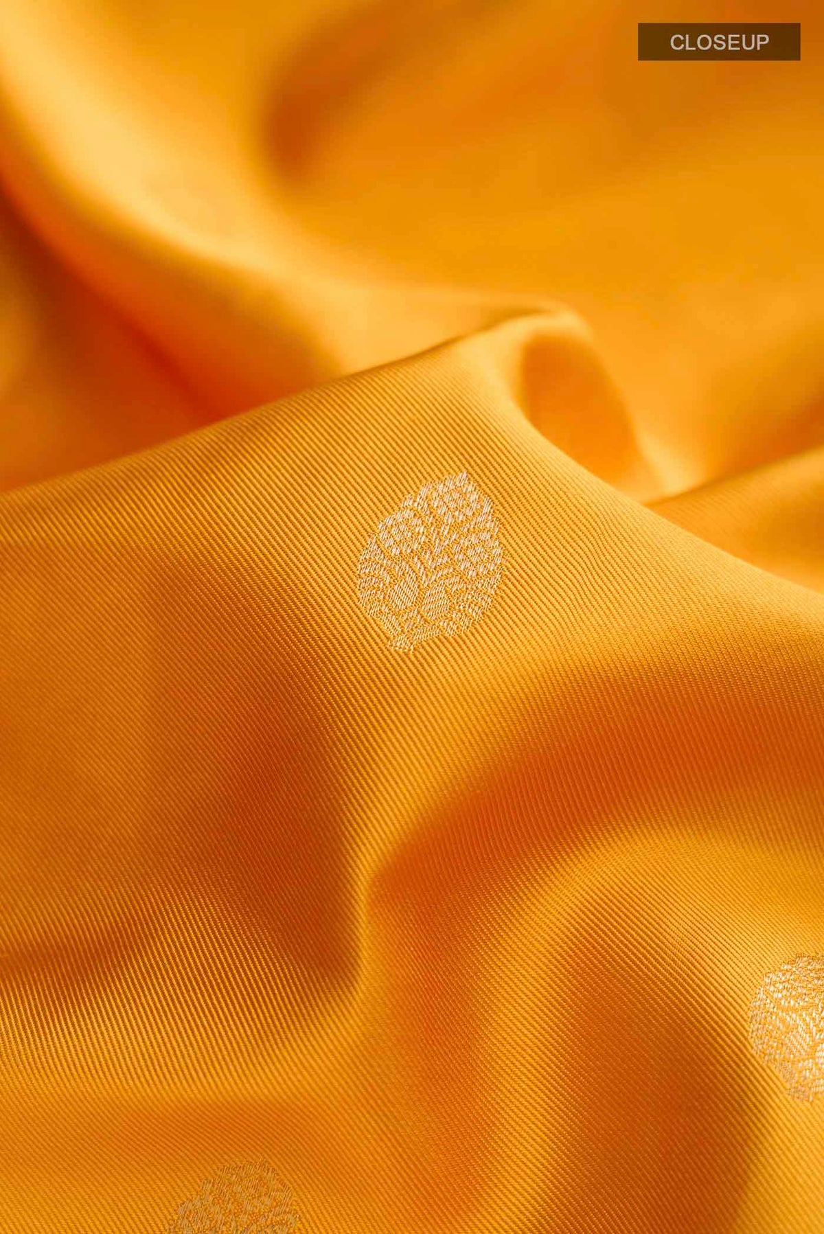 Close up of Yellow Soft Silk Saree with Zari Butta on the body and Zari Border displaying folds