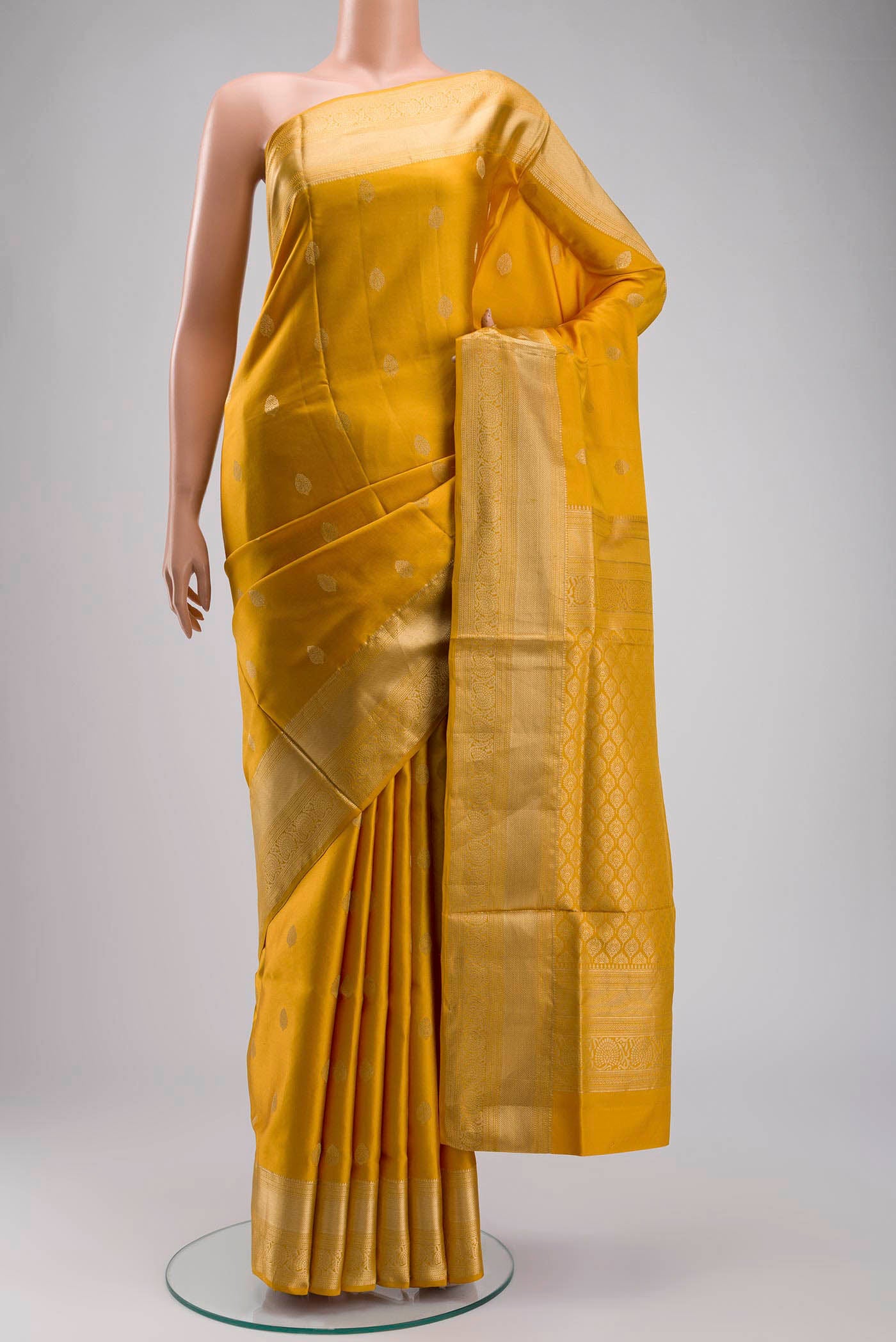 Yellow Soft Silk Saree with Zari Butta on the body and Zari Border displayed on a mannequin