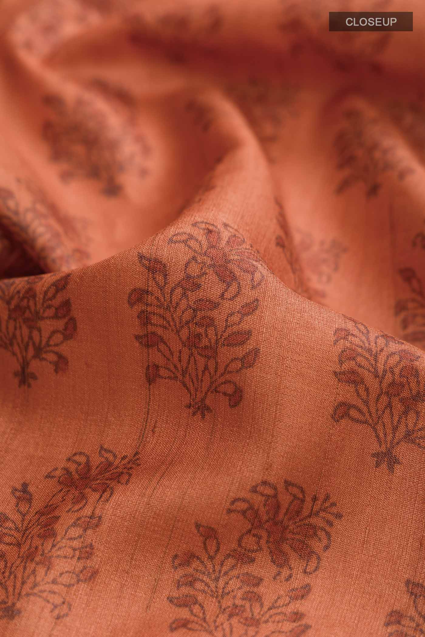 Close up of Orange Tussar Silk Saree with Printed design on the body and Plain Border displaying folds
