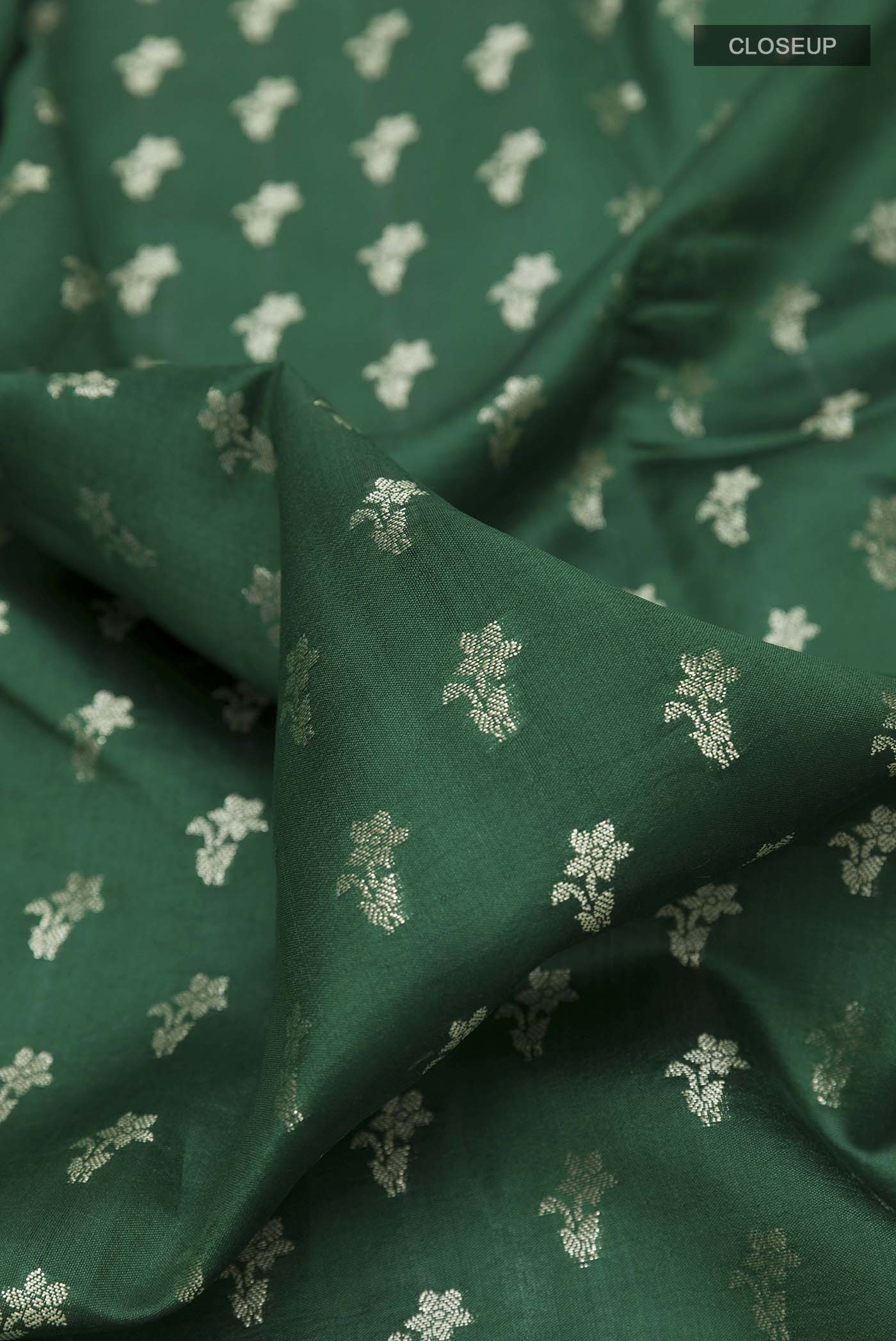 Close up of Green Banarasi Raw Silk Saree with Zari Butta on the body and Zari Border displaying folds