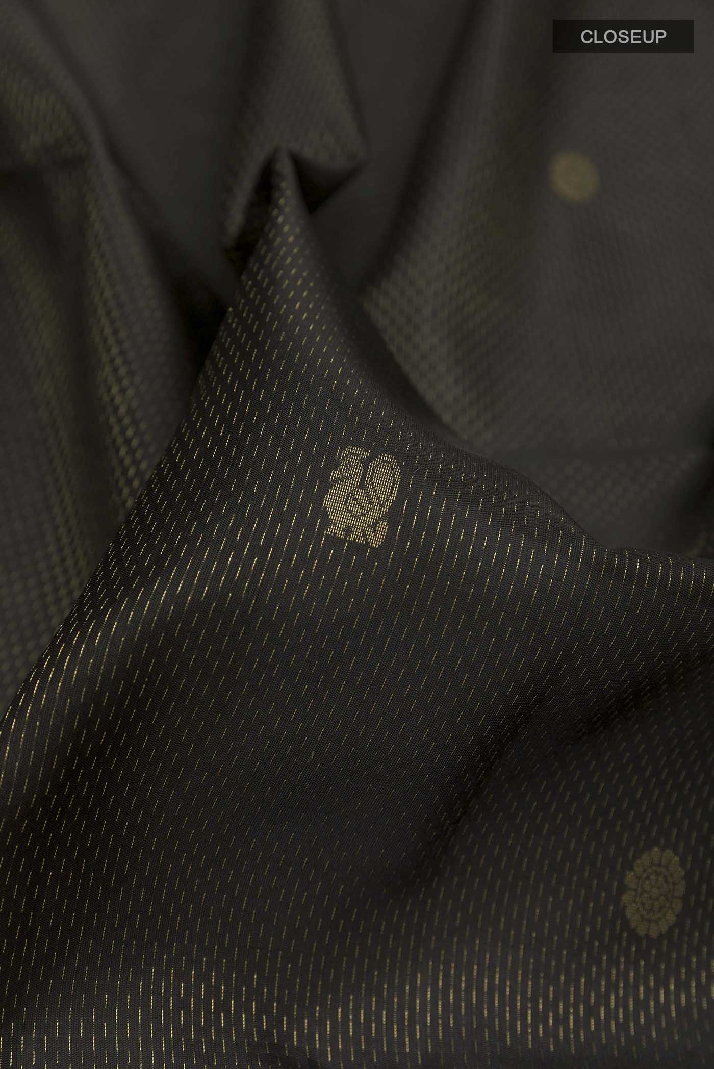 Close up of Black Soft Silk Saree with Zari Butta on the body and Zari Border displaying folds