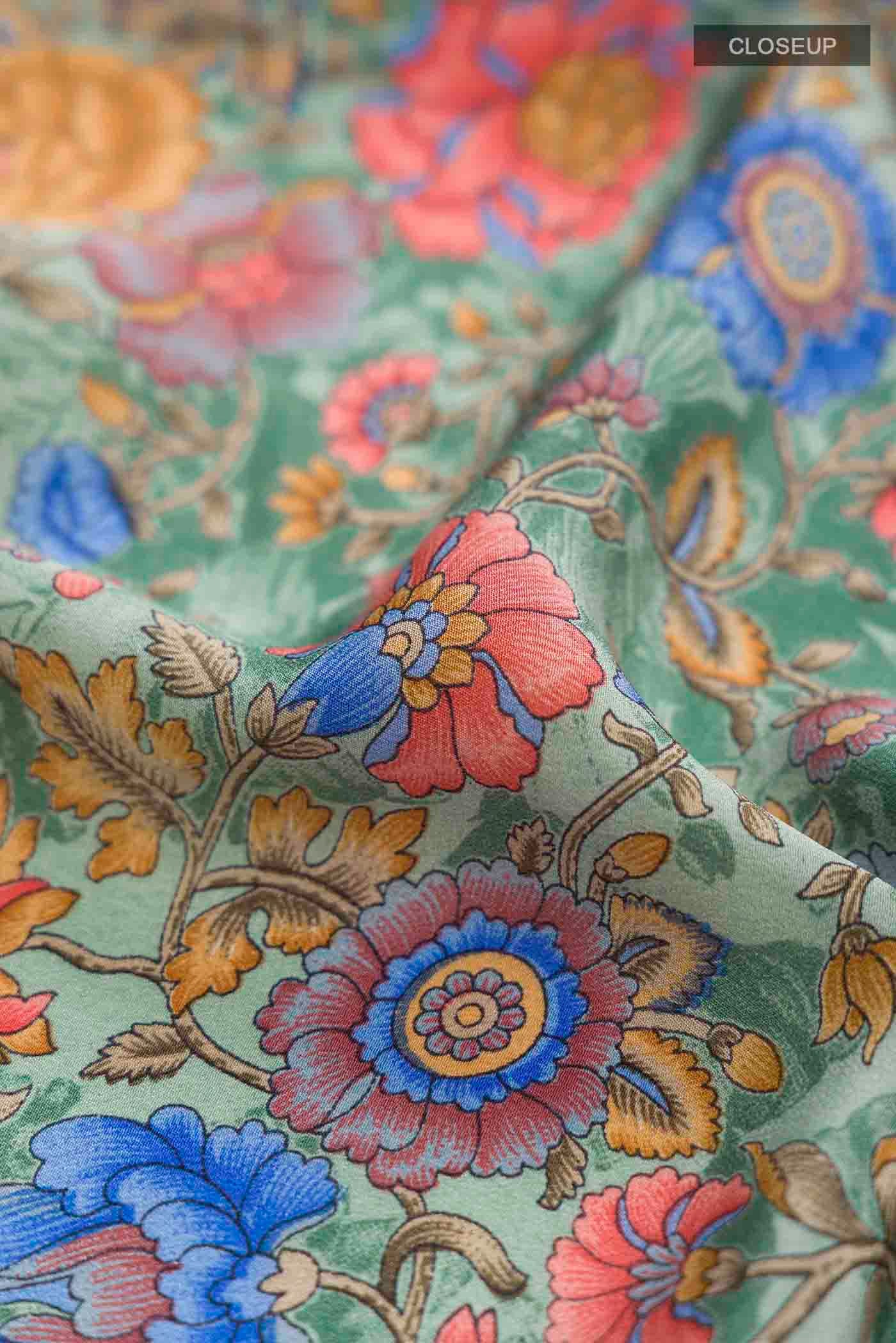 Close up of Sage Green Crepe Saree with Printed design on the body and Printed Border displaying folds