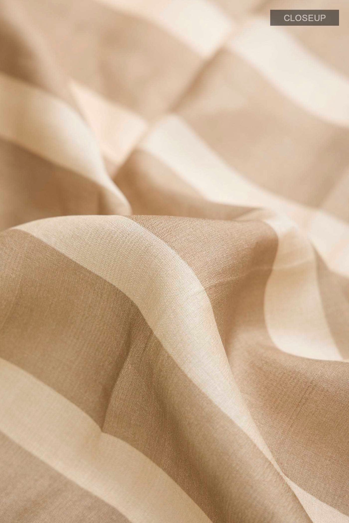 Close up of Beige Tussar Silk Saree with Stripes on the body and Zari Border displaying folds