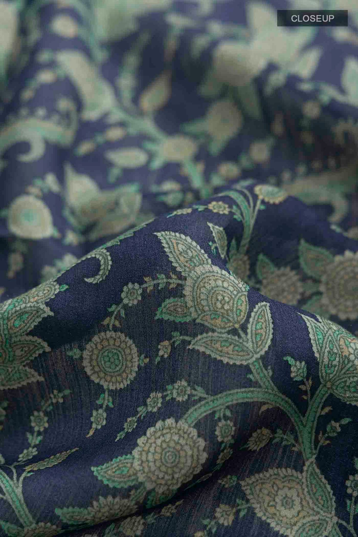Close up of Blue Tussar Silk Saree with Printed design on the body and Zari Border displaying folds