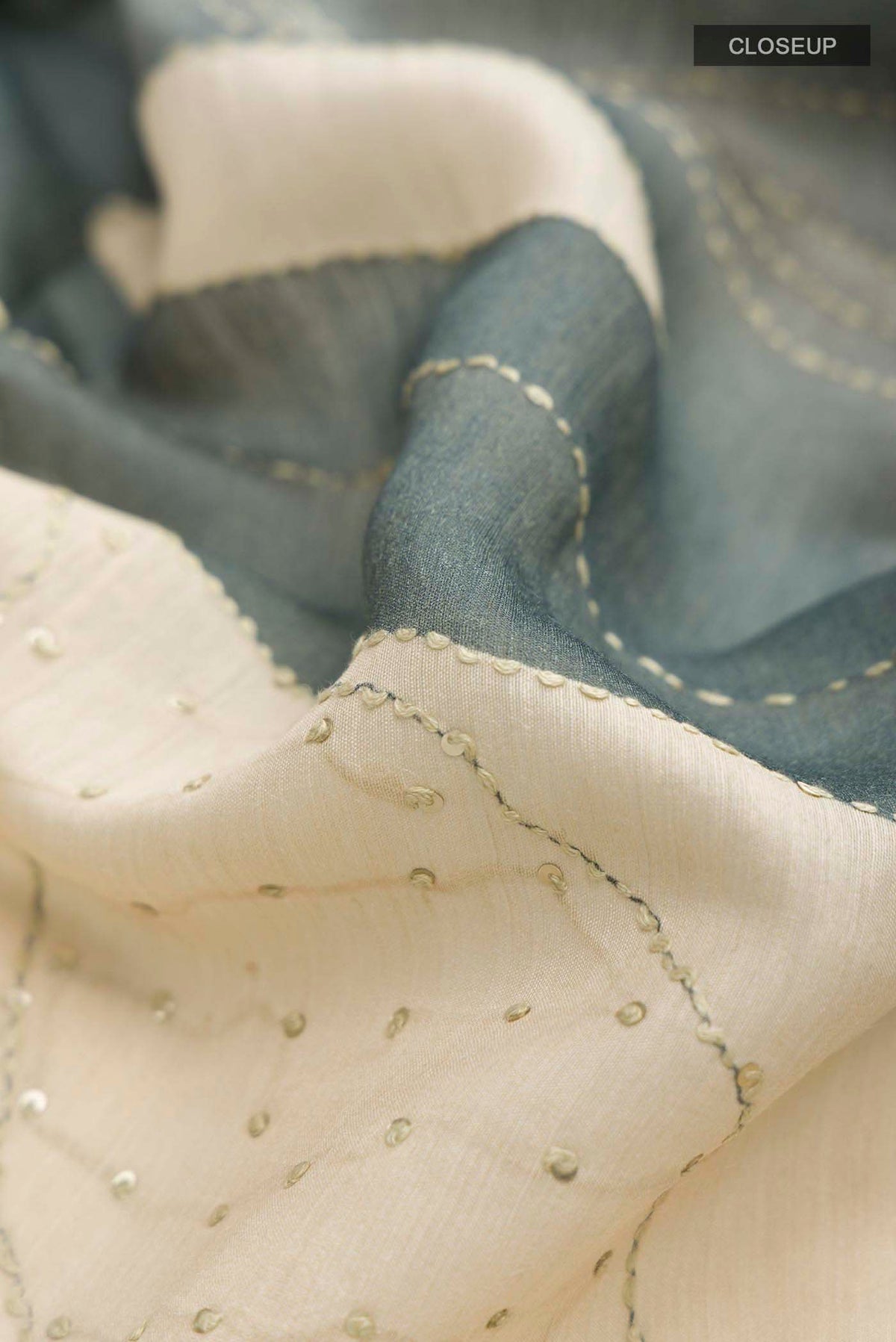Close up of Cream Tussar Silk Saree with Embroidery on the body and Zari Border displaying folds