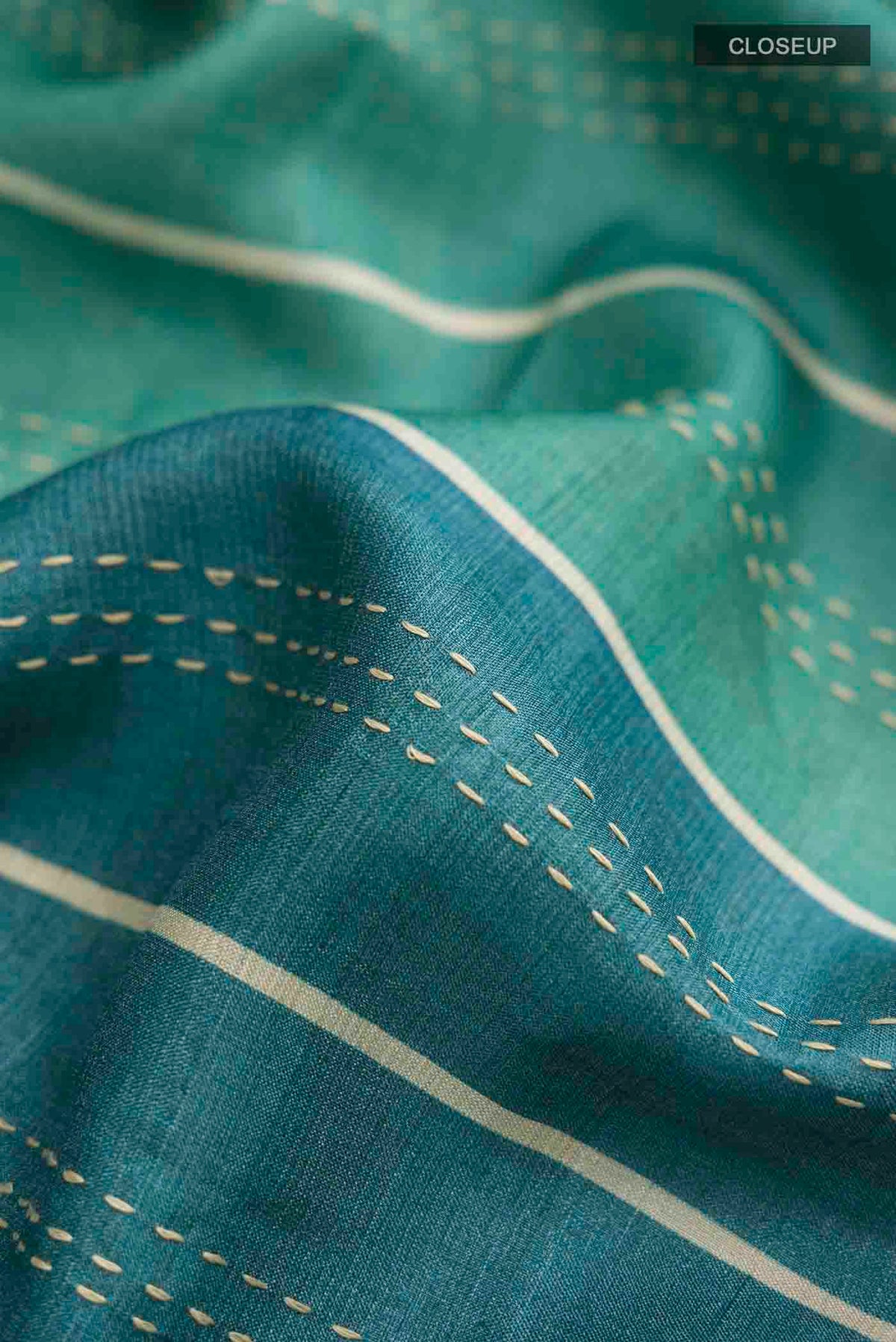 Close up of Green Tussar Silk Saree with Embroidery on the body and Zari Border displaying folds