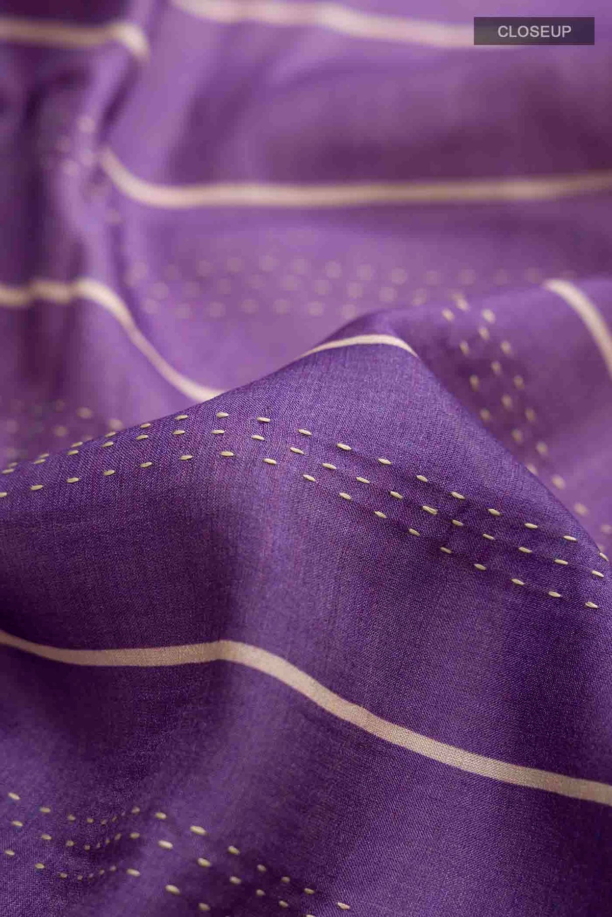 Close up of Lavender Tussar Silk Saree with Embroidery on the body and Zari Border displaying folds