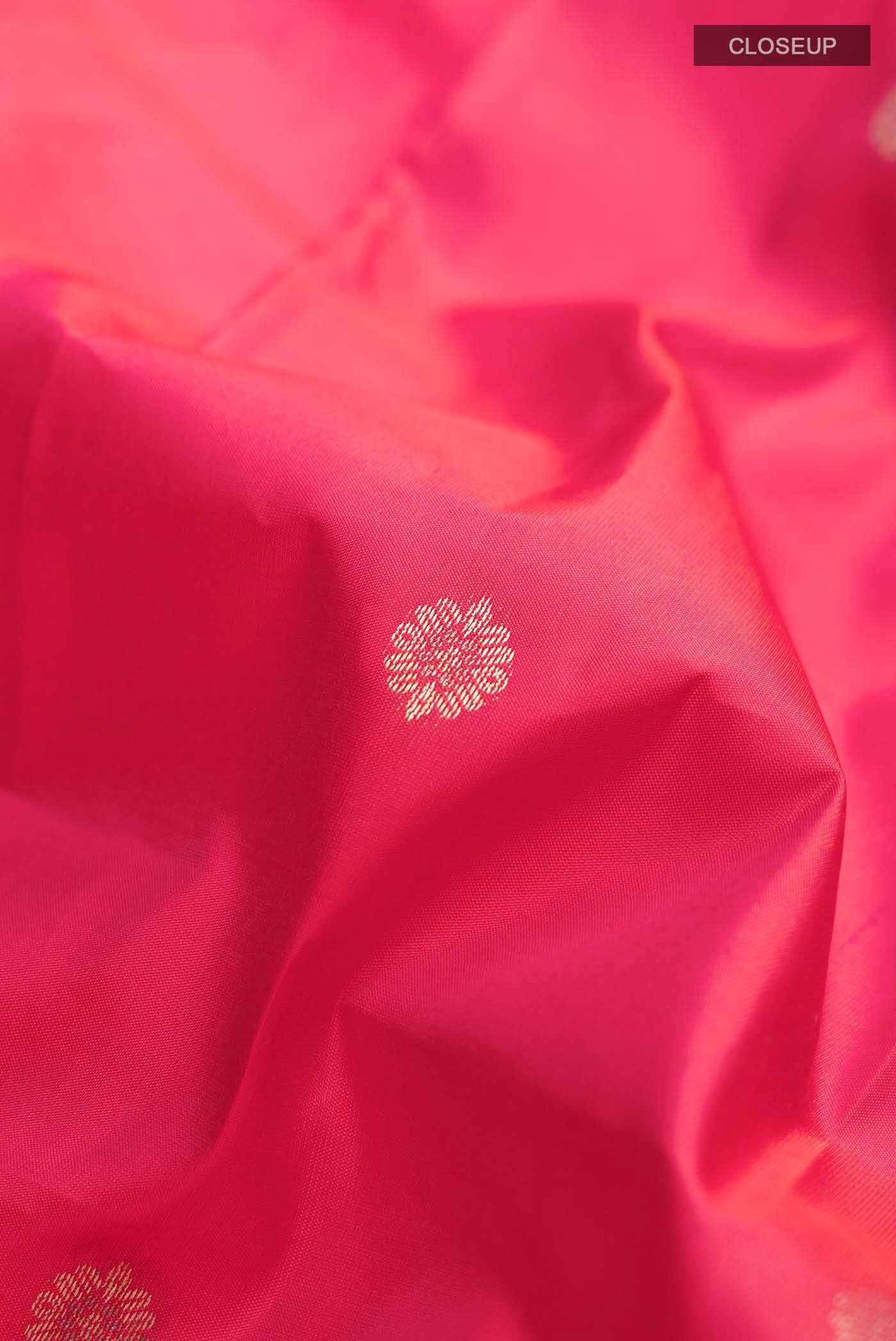 Close up of Coral Kanchipuram Silk Saree with Zari Butta on the body and Zari Border displaying folds