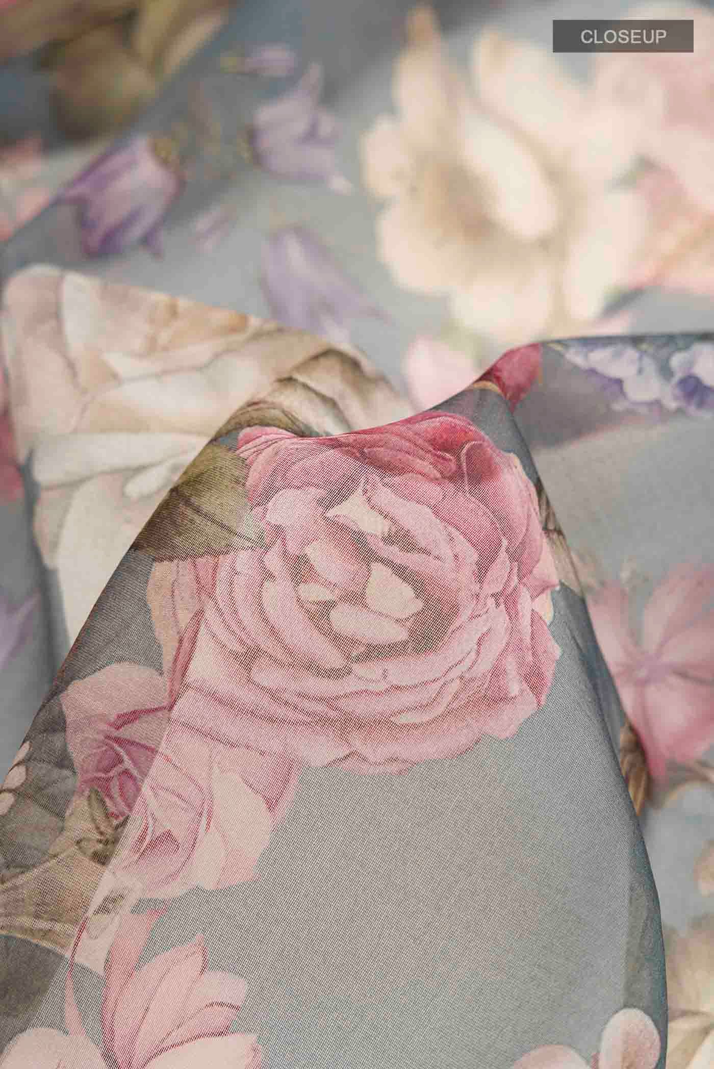 Close up of Grey Organza Silk Saree with Printed design on the body and Zari Border displaying folds