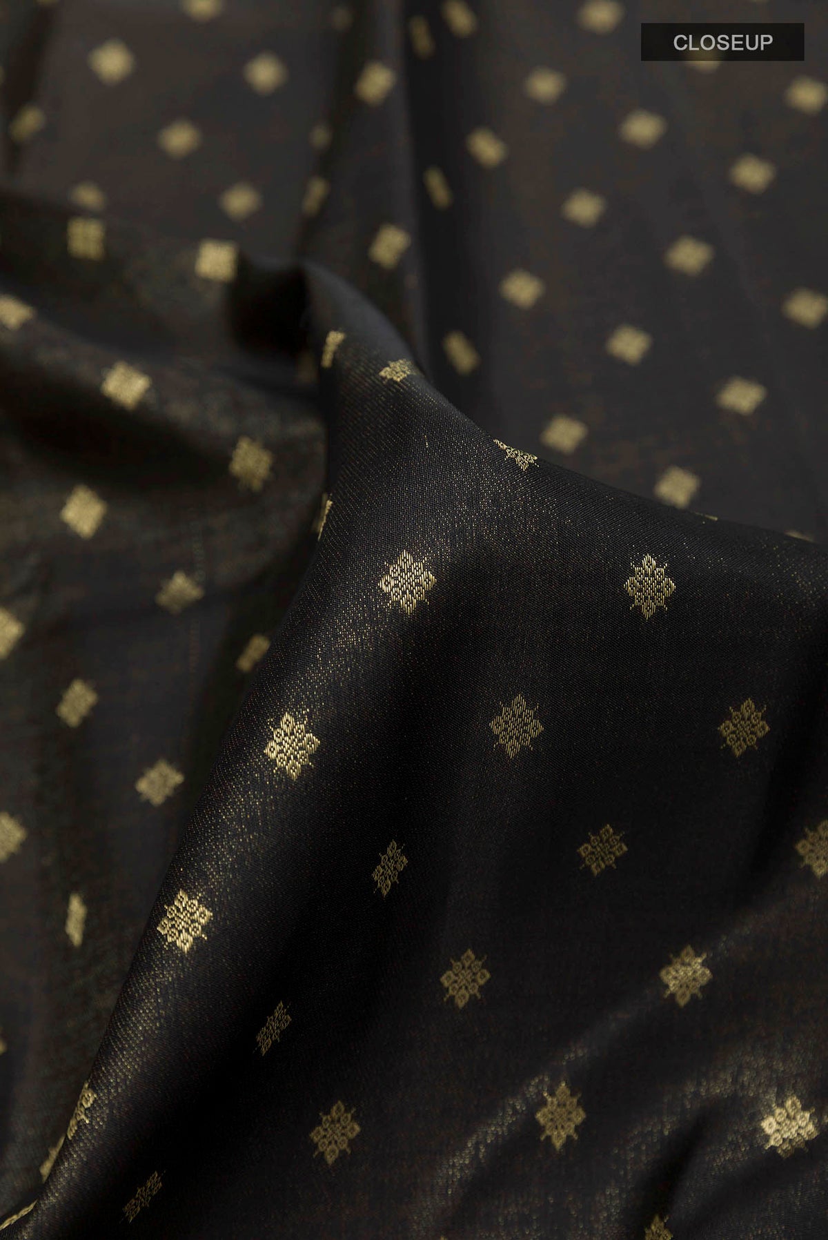 Close up of Black Kanchipuram Silk Saree with Zari Butta on the body and Zari Border displaying folds