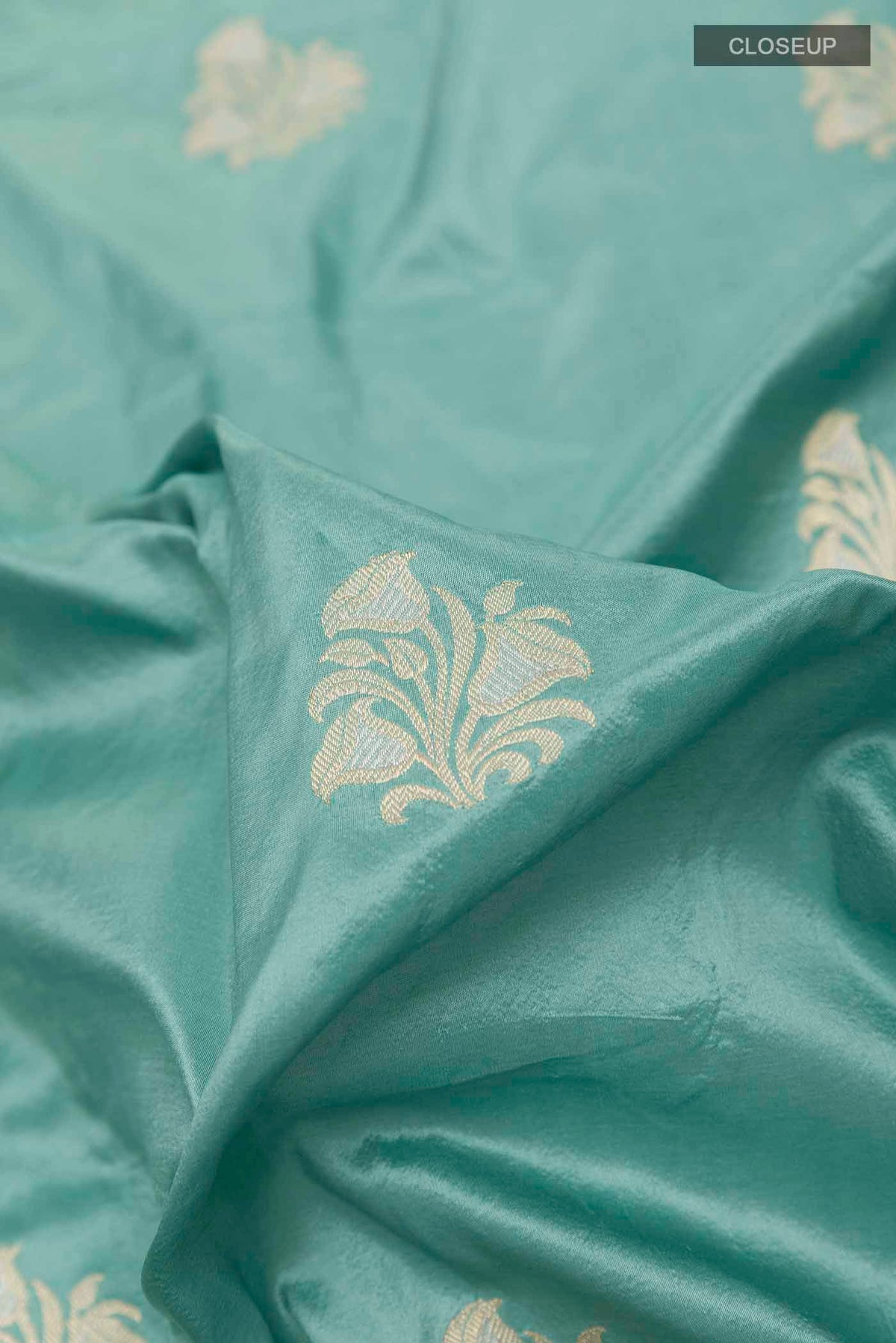 Close up of Blue Grey Banarasi Silk Saree with Zari Butta on the body and Zari Border displaying folds