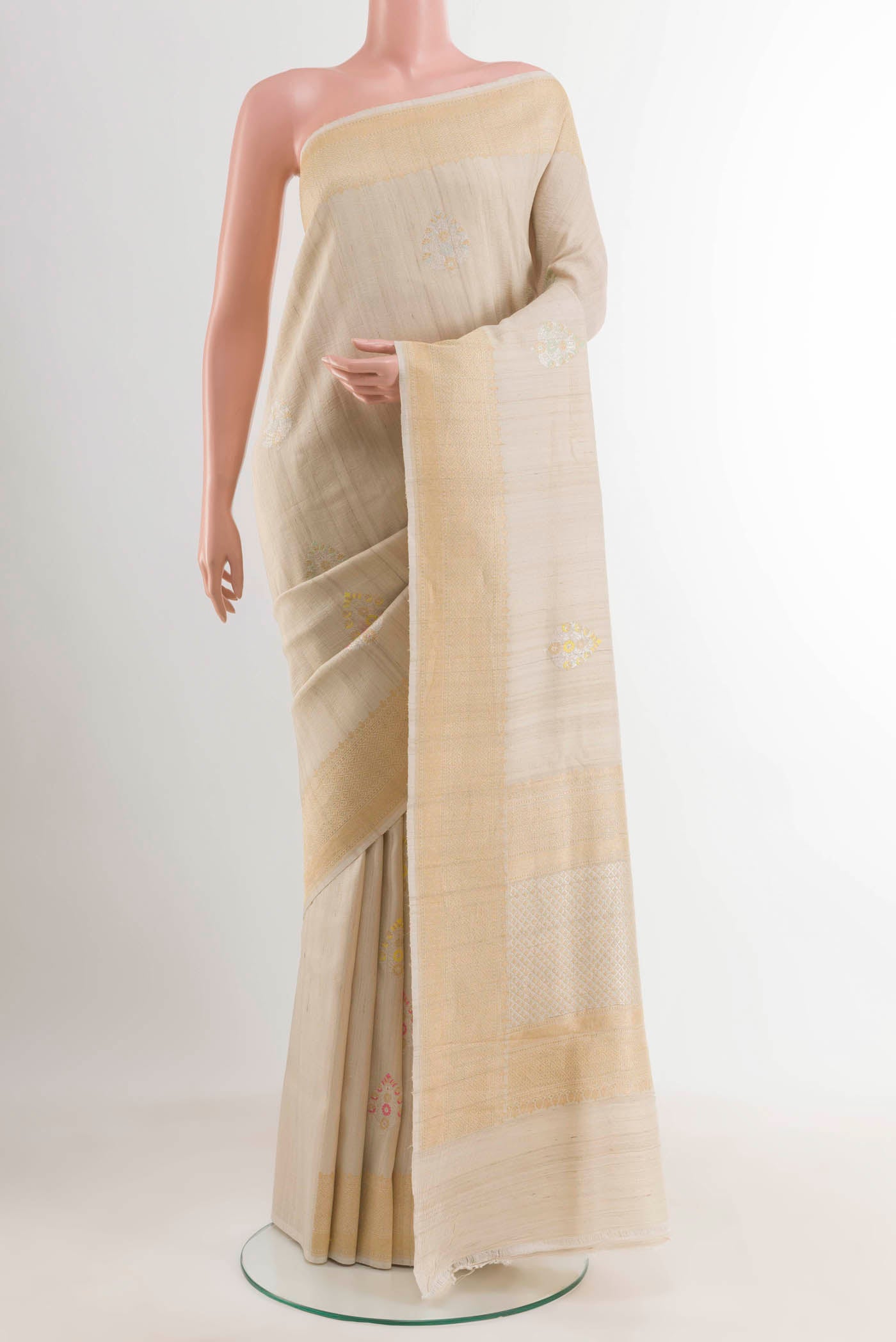 Cream Tussar Saree with Zari Butta on the body and Zari Border displayed on a mannequin
