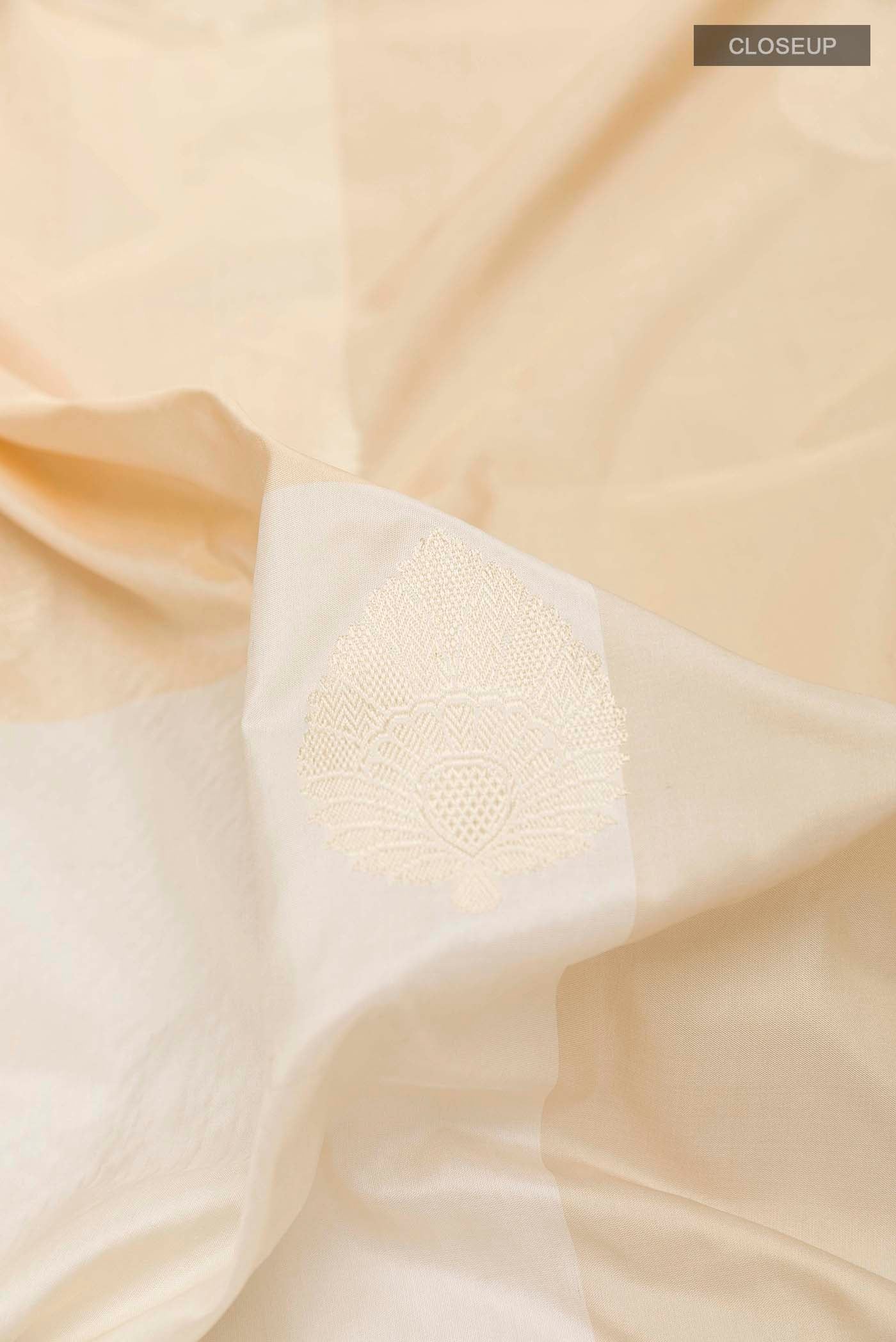 Close up of Off White Banarasi Silk Saree with Zari Butta on the body and Zari Border displaying folds