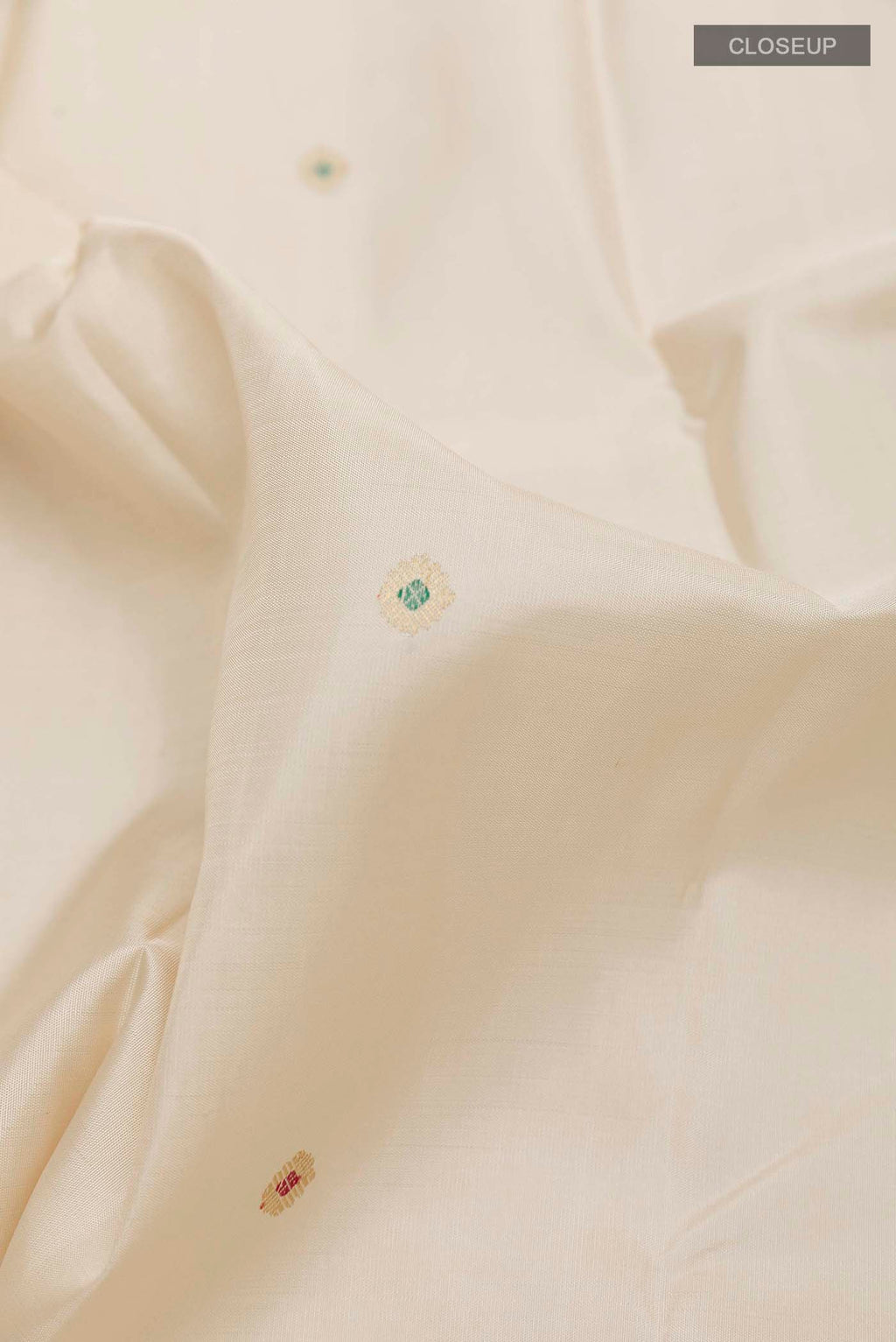 Close up of Off White Kanchipuram Silk Saree with Zari Butta on the body and Zari Border displaying folds