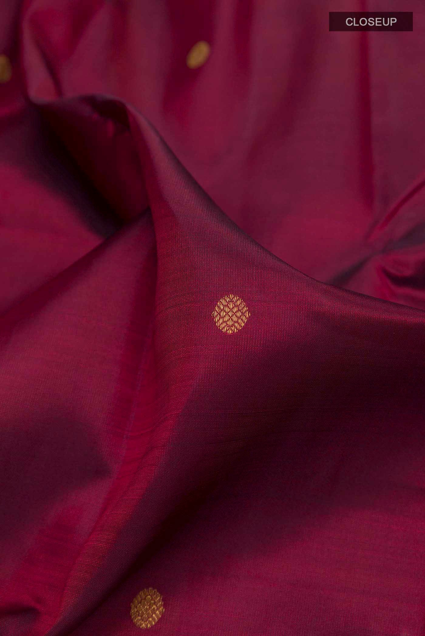 Close up of Pure Silk Pure Zari Maroon Dual Tone Kanchipuram Saree with Zari Butta on the body and Zari Border displaying folds