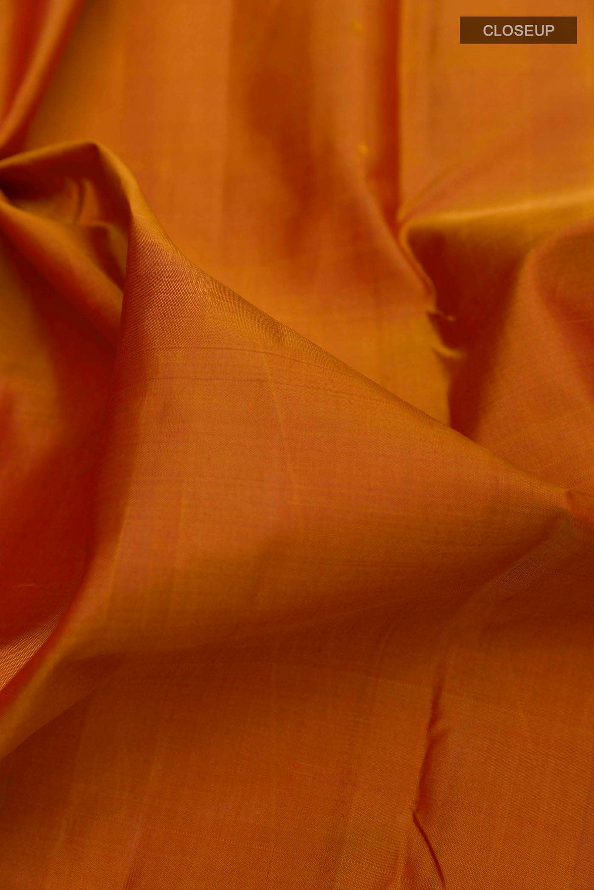 Close up of Brick Orange Kanchipuram Silk Saree with Plain Body and Zari Border displaying folds
