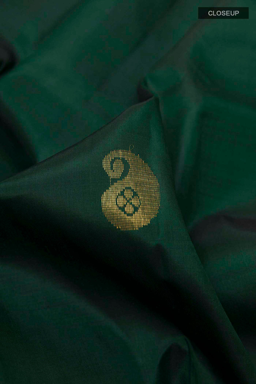 Close up of Bottle Green Kanchipuram Silk Saree with Zari Butta on the body and Zari Border displaying folds
