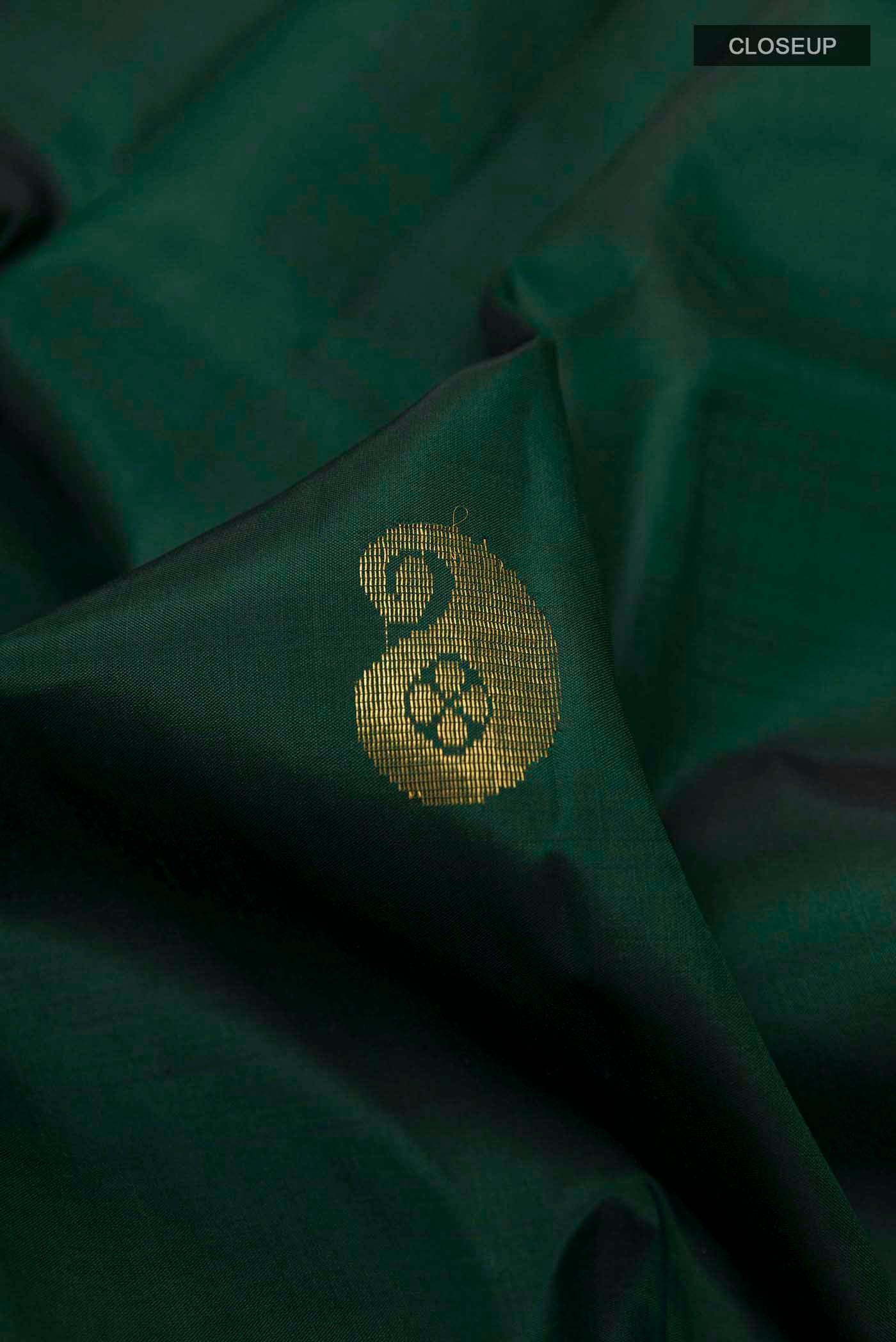 Close up of Bottle Green Kanchipuram Silk Saree with Zari Butta on the body and Zari Border displaying folds