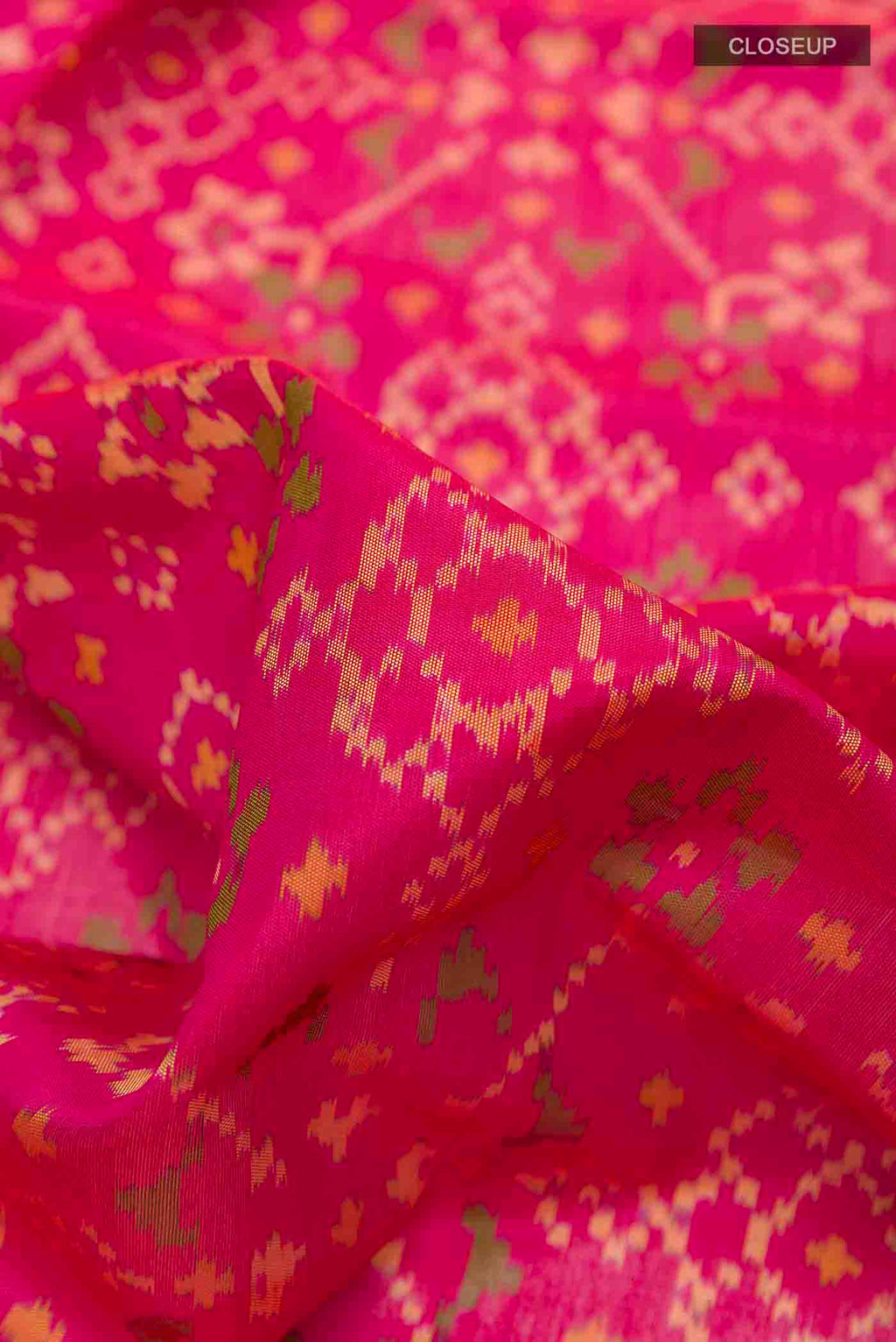 Close up of Pink Rajkot Patola Silk Saree with Ikat design on the body and Zari Border displaying folds